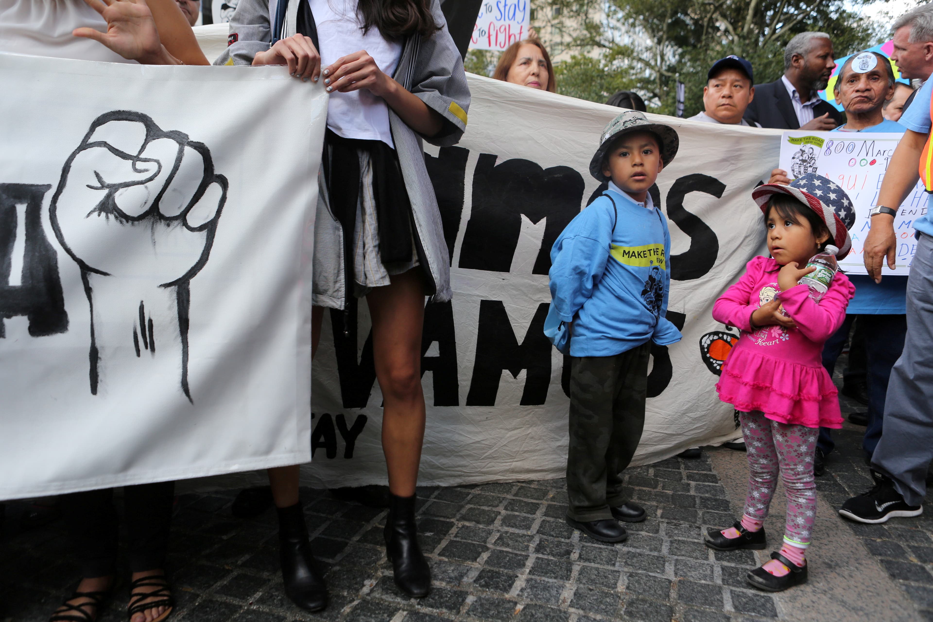 Children stand next to a banner against the US President's proposed end of the DACA program