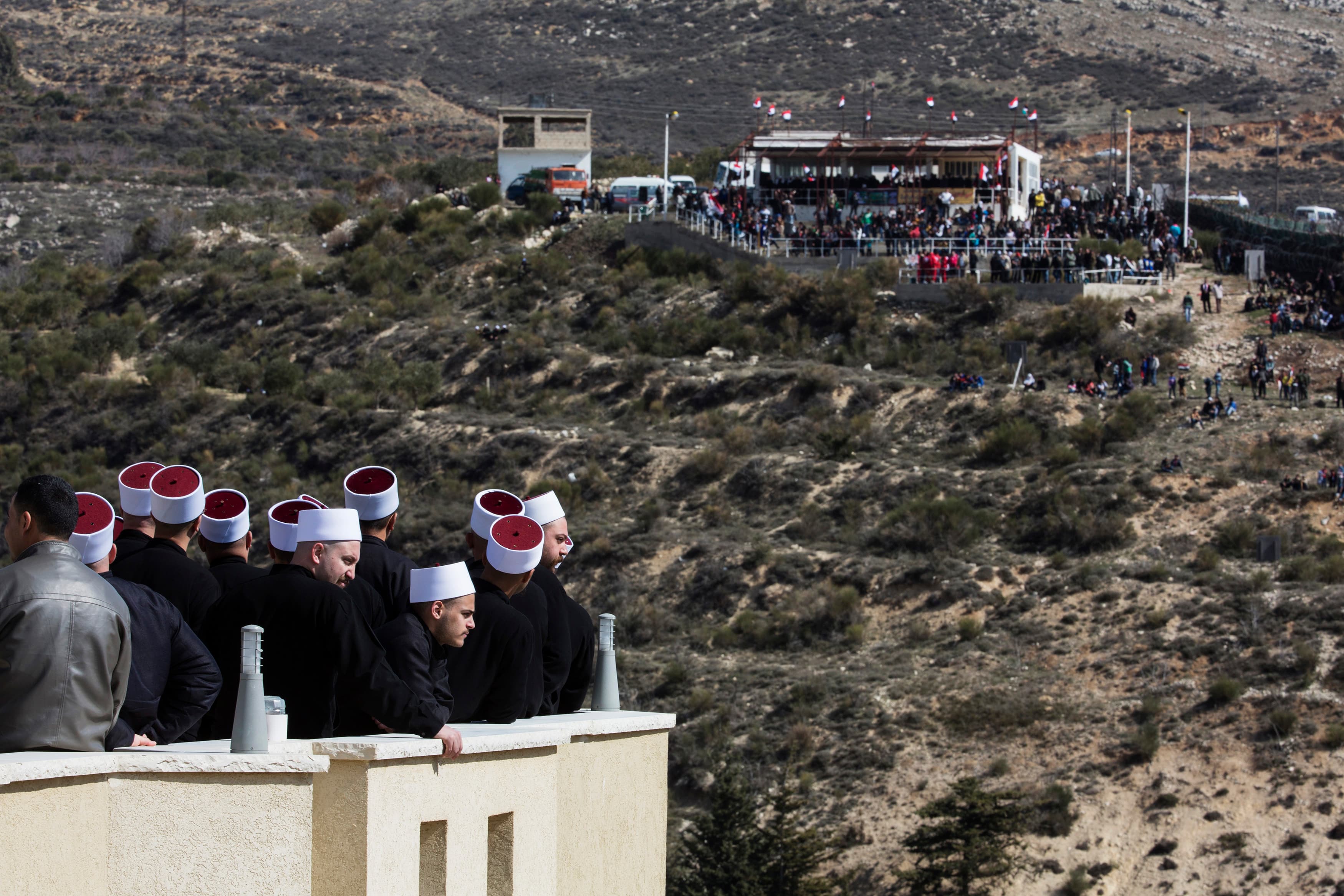 Members of the Druze community look at their friends and relatives on the Syrian side of the border, during a rally in the Druze village of Majdal Shams on the Israel-occupied Golan Heights, Feb. 14, 2014.