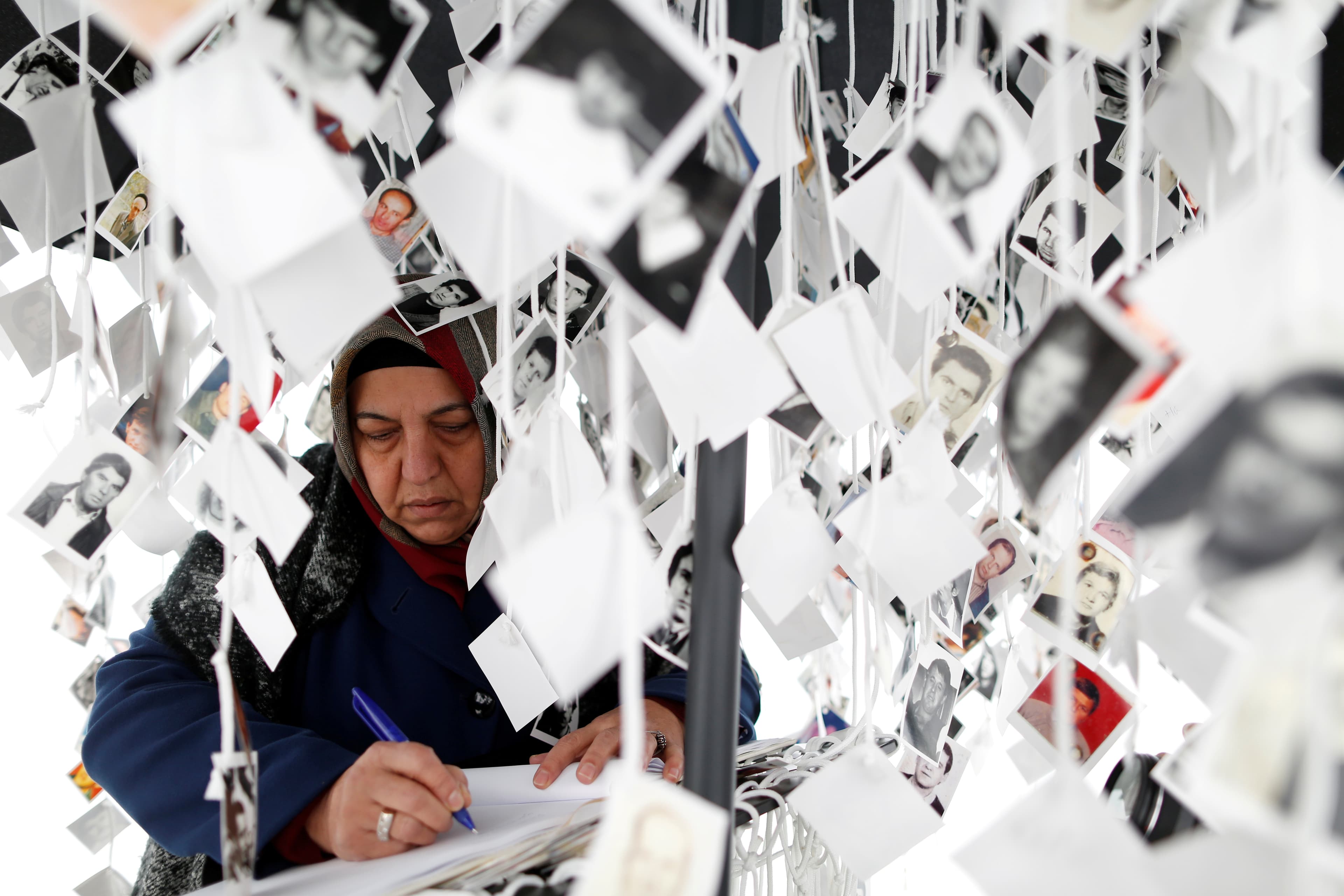 A woman writes in a book inside a traveling monument called 'Prijedor 92' outside the Yugoslav War Crimes Tribunal (ICTY