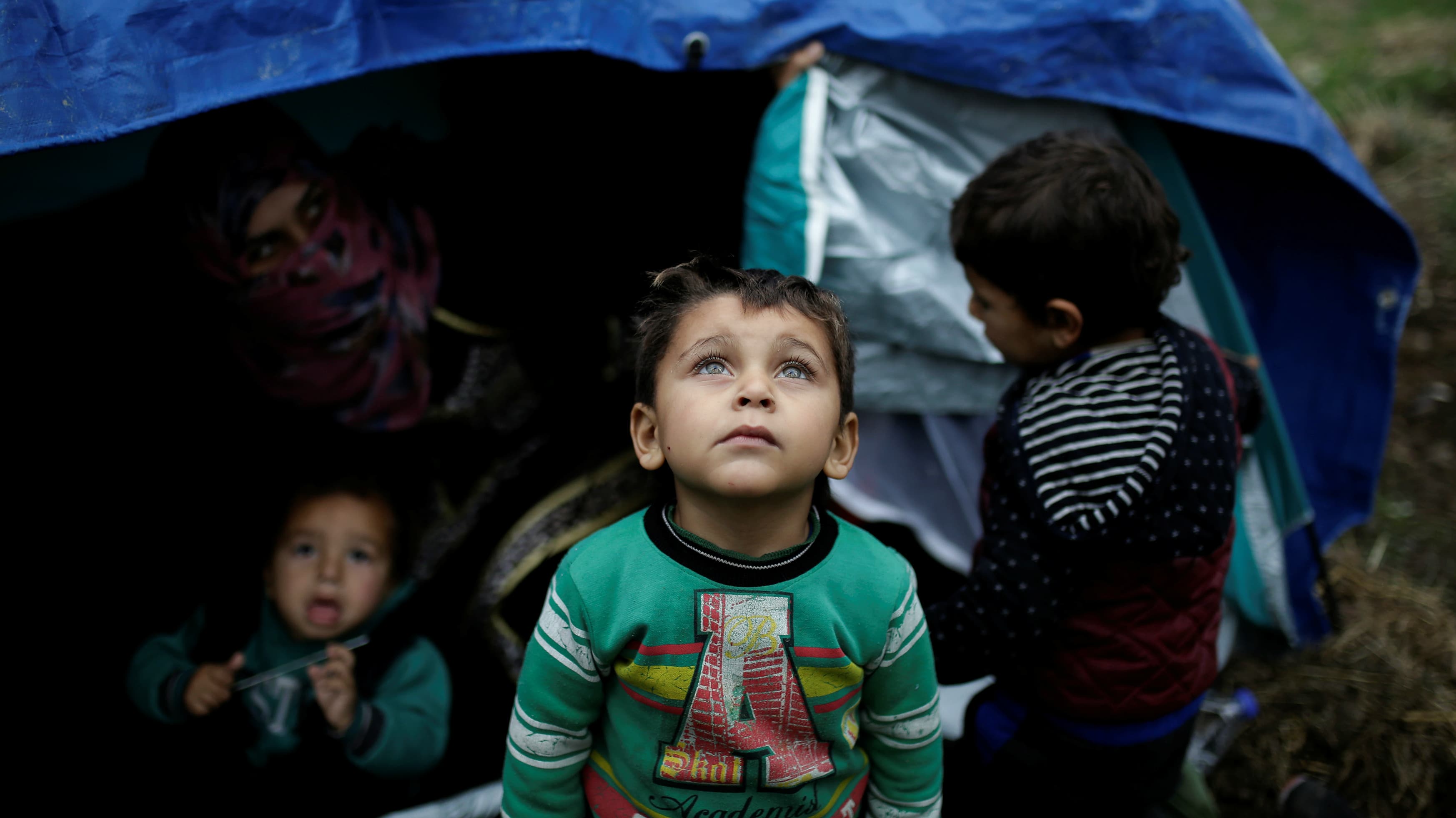 A Syrian refugee boy stands in front of his family tent at a makeshift camp for refugees and migrants next to the Moria camp on the Greek island of Lesbos, Nov. 30, 2017.