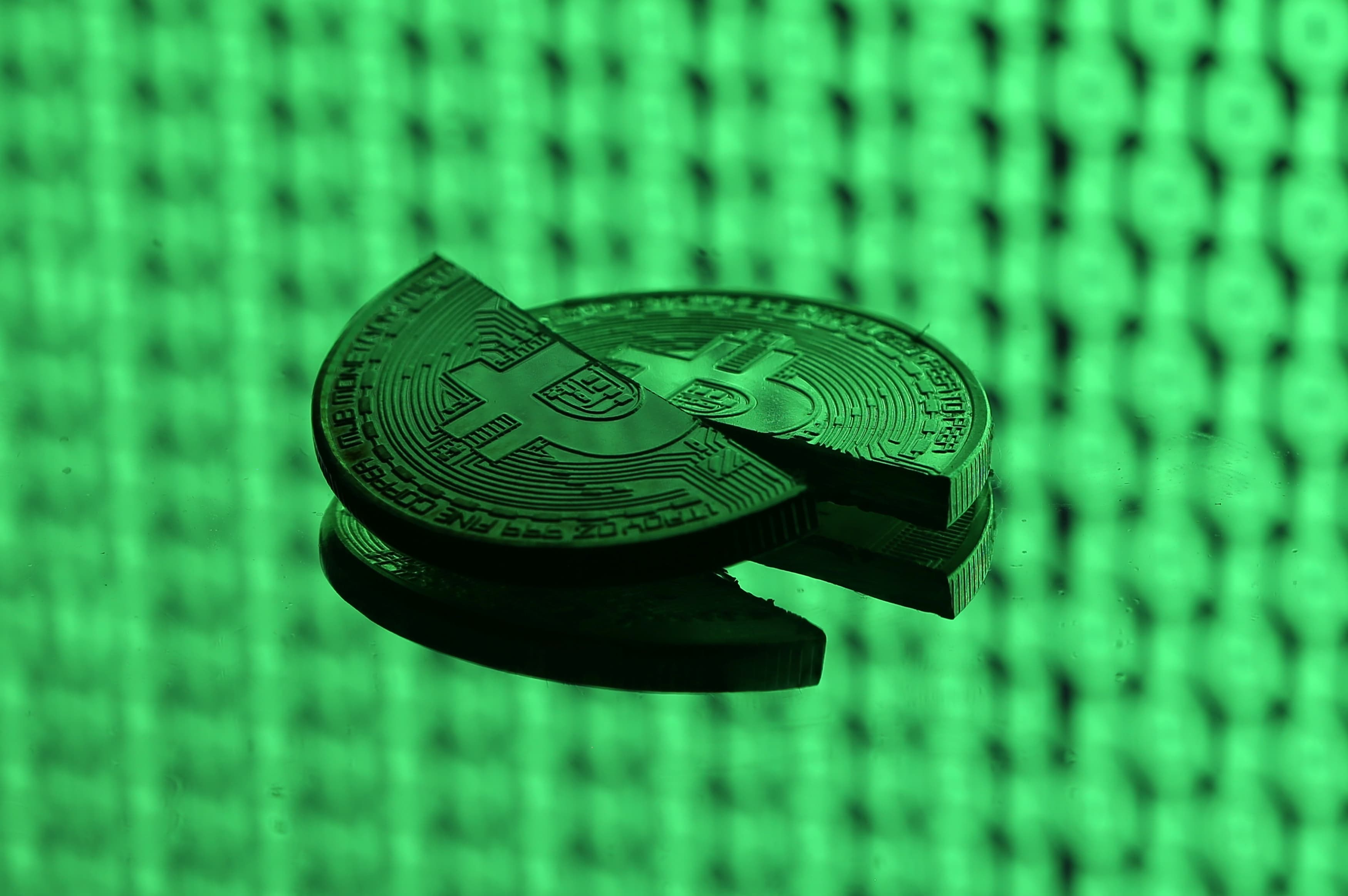 Broken representations of the bitcoin virtual currency, placed on a monitor that displays binary digits, are seen in this illustration picture, December 8, 2017.