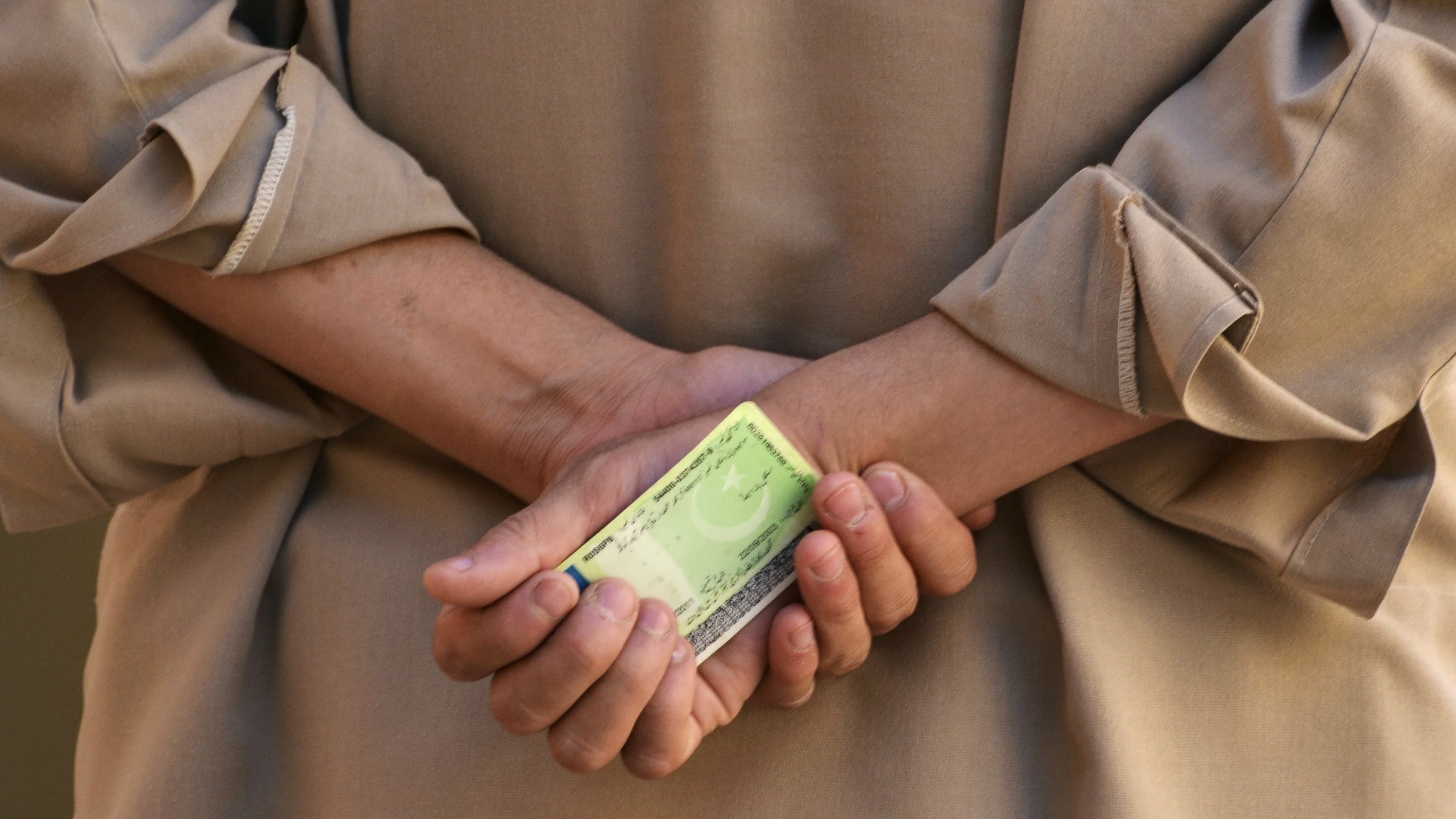A voter holds his national identity card as he waits to cast his vote at a polling station in Quetta, Pakistan, May 11, 2013.