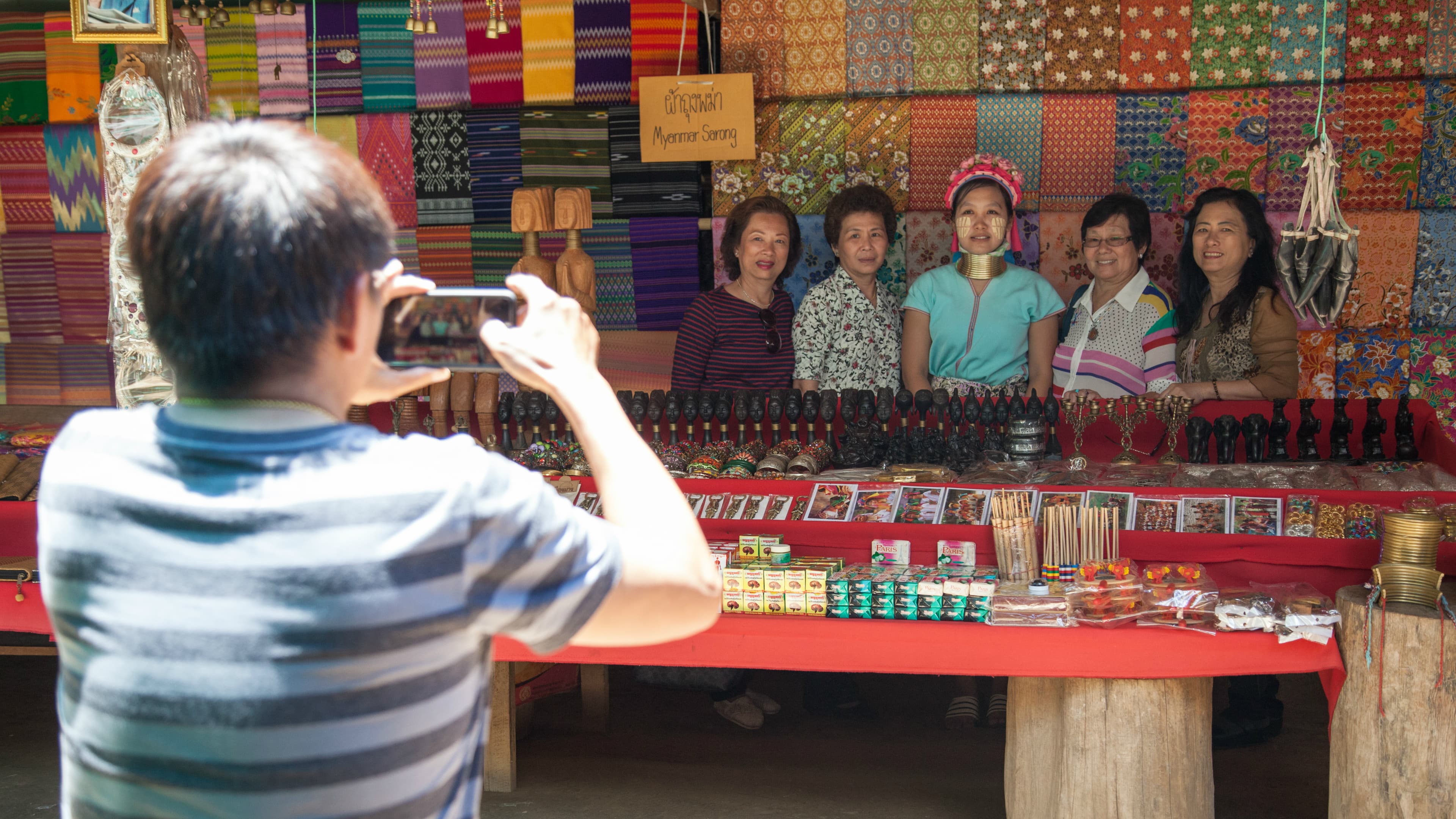 Thai tourists from Bangkok take a photo with one of the women at Huai Sua Tao.