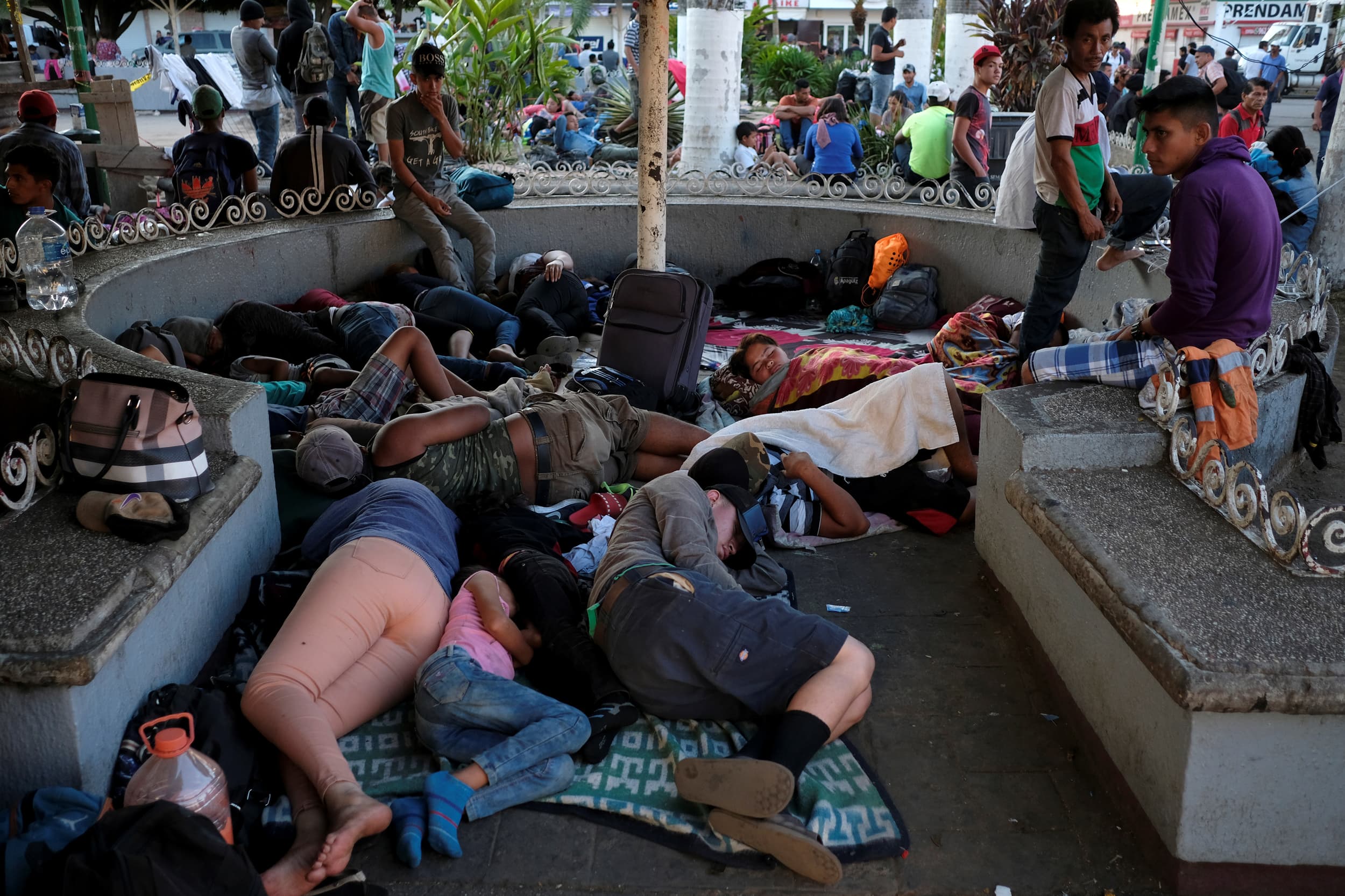 A group of people sleep in a concrete structure in a public park