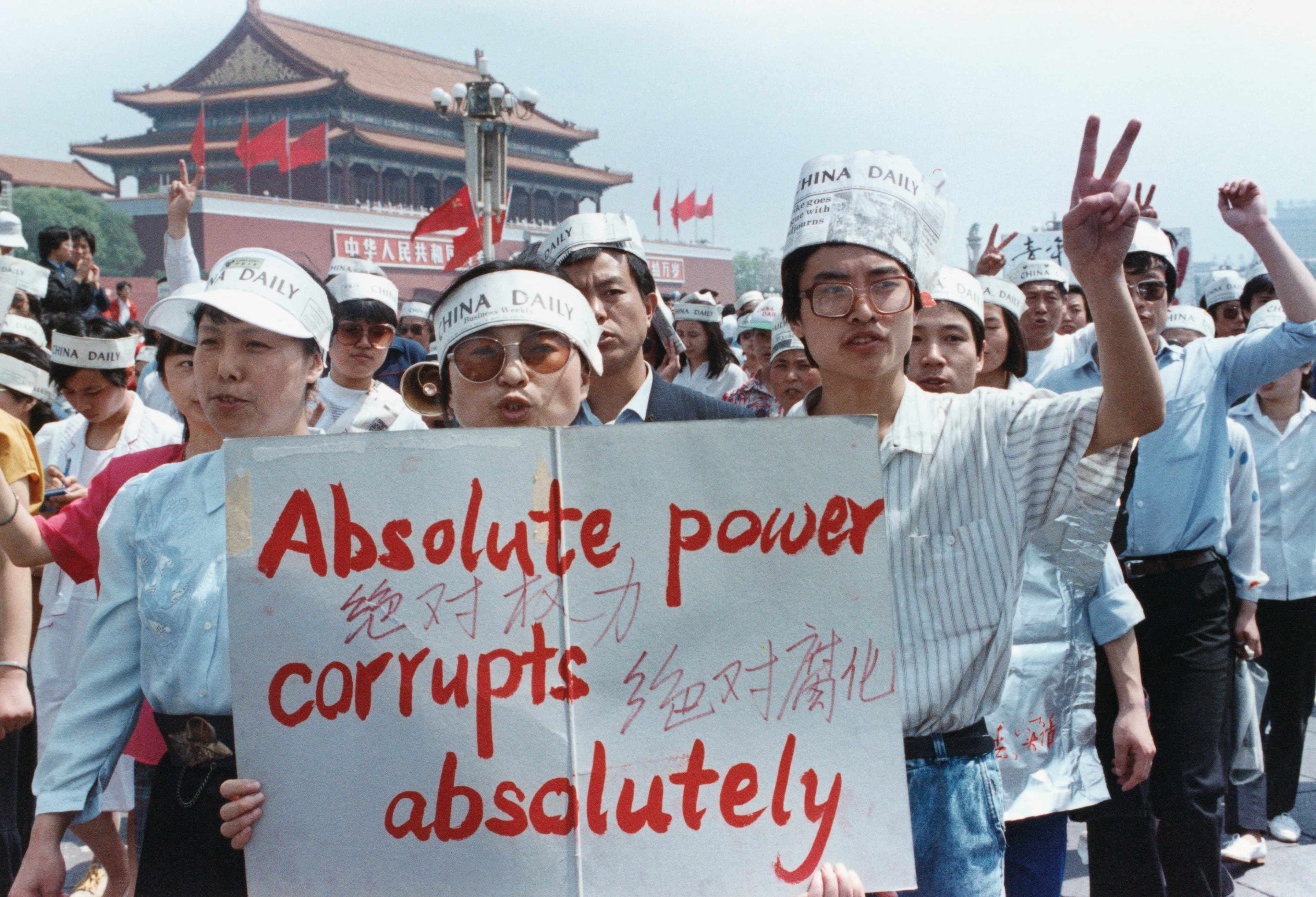 Protesters in Tiananmen Square hold up a sign that says absolute power corrupts absolutely.