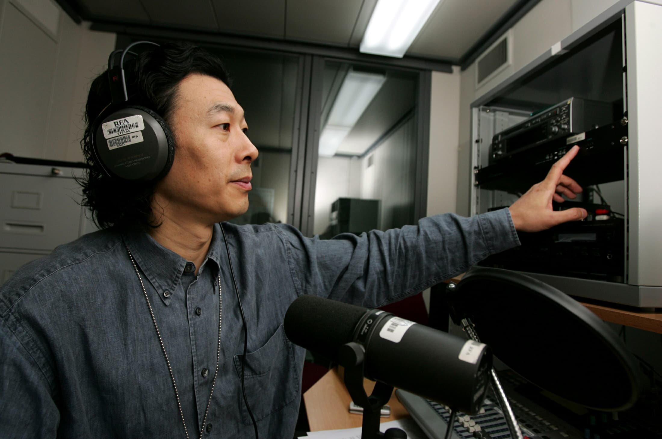 A man with headphones on speaks into a microphone in a studio.