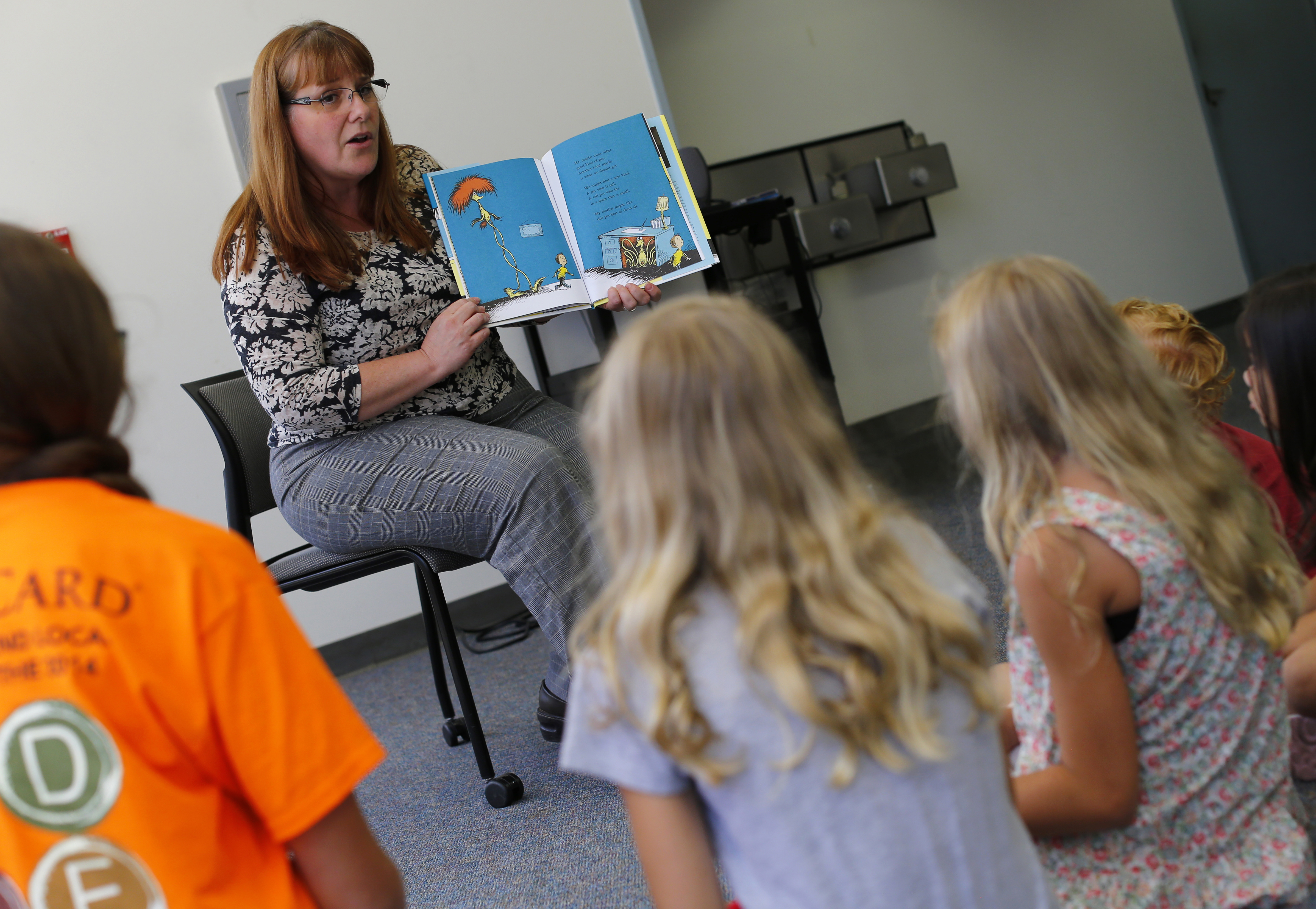 a teacher reads a book to a group of student.