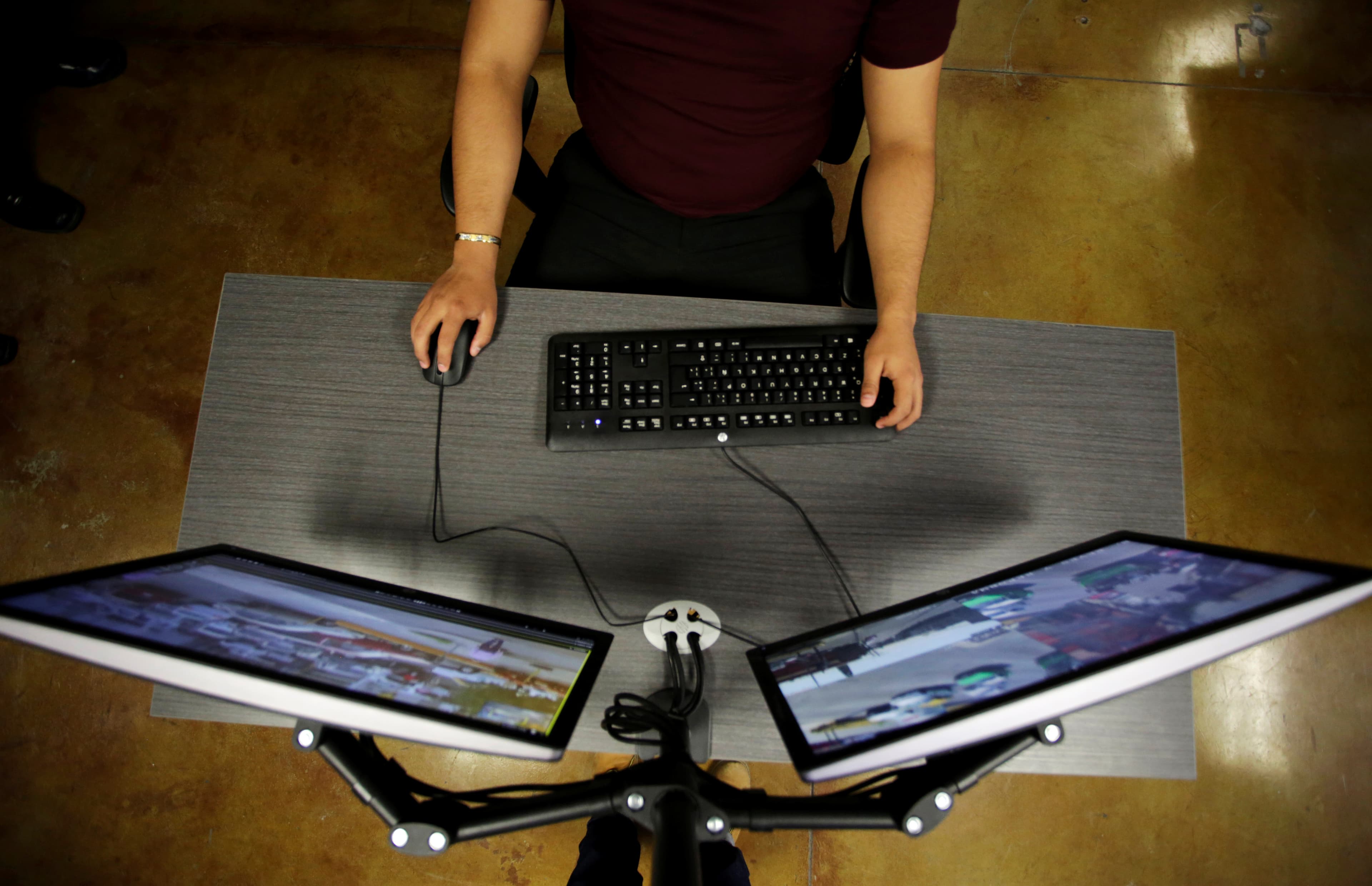 A man sits in front of two computer monitors.