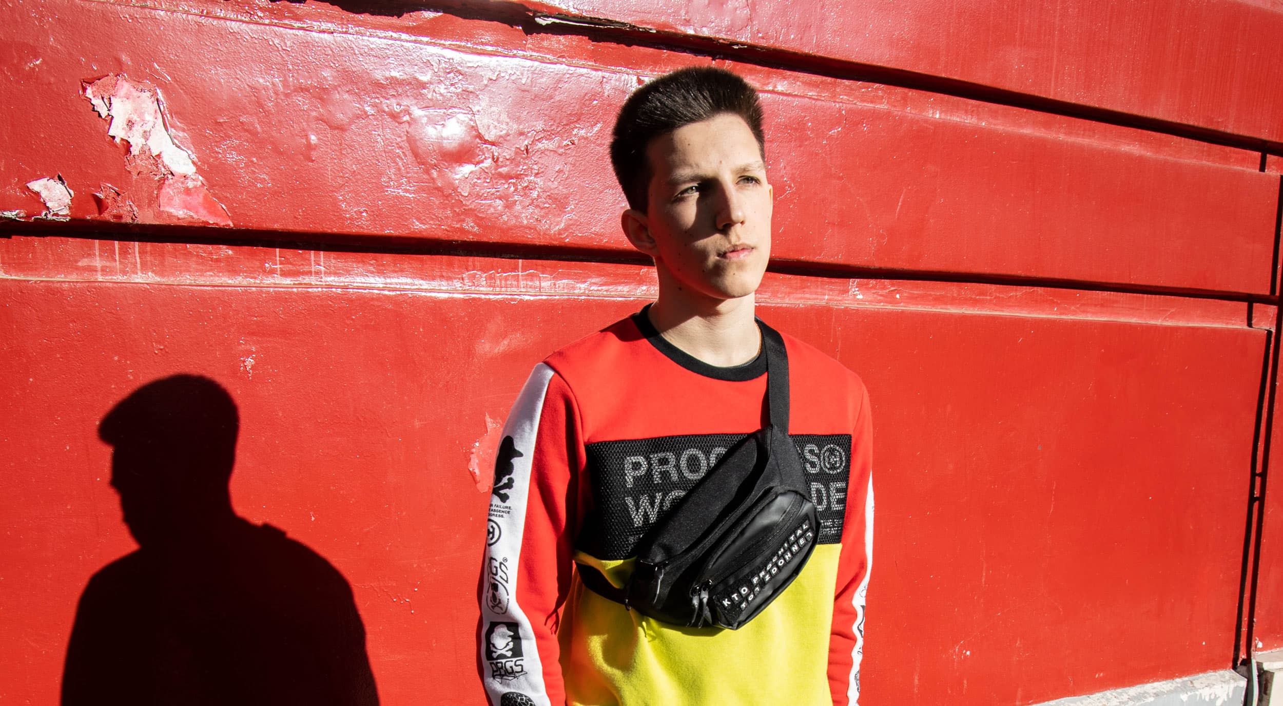 A man poses in front of a red wall.