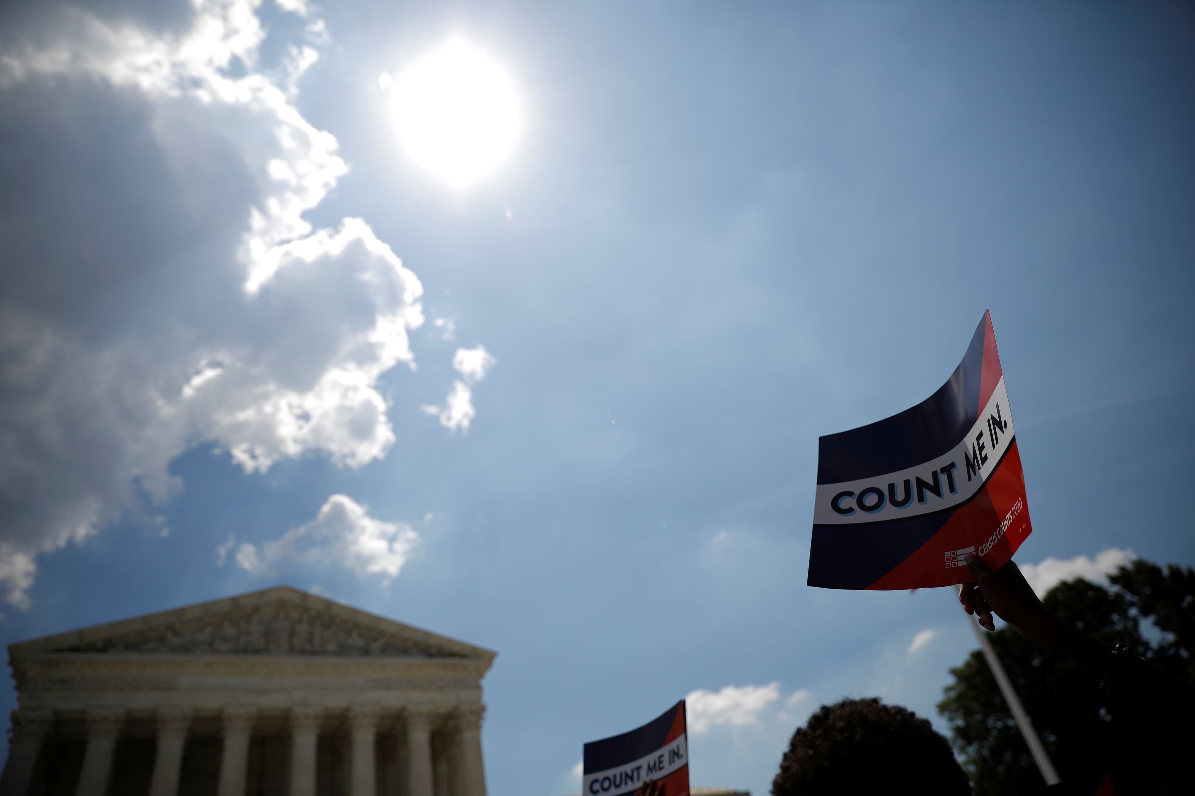 A sign that says "Count Me In" with the US Supreme Court building in the background
