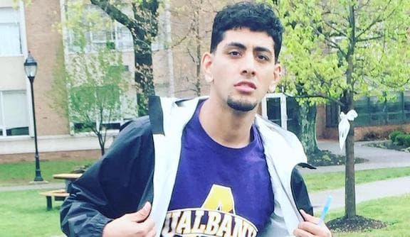 A young man shows his college shirt