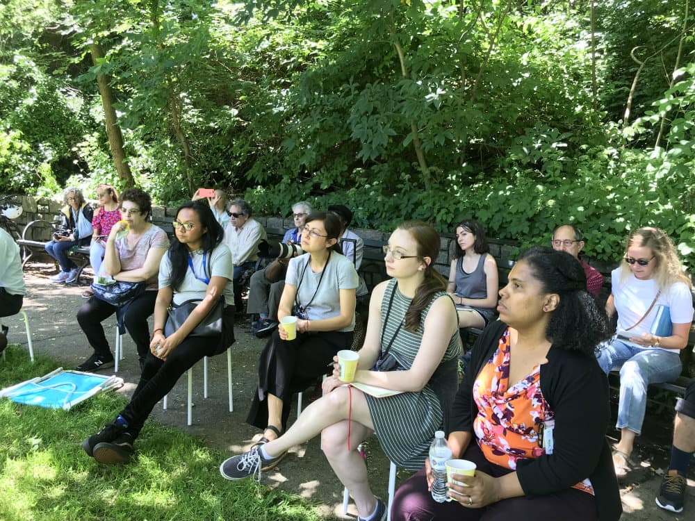 People sit on folding chairs listening to a lecture.