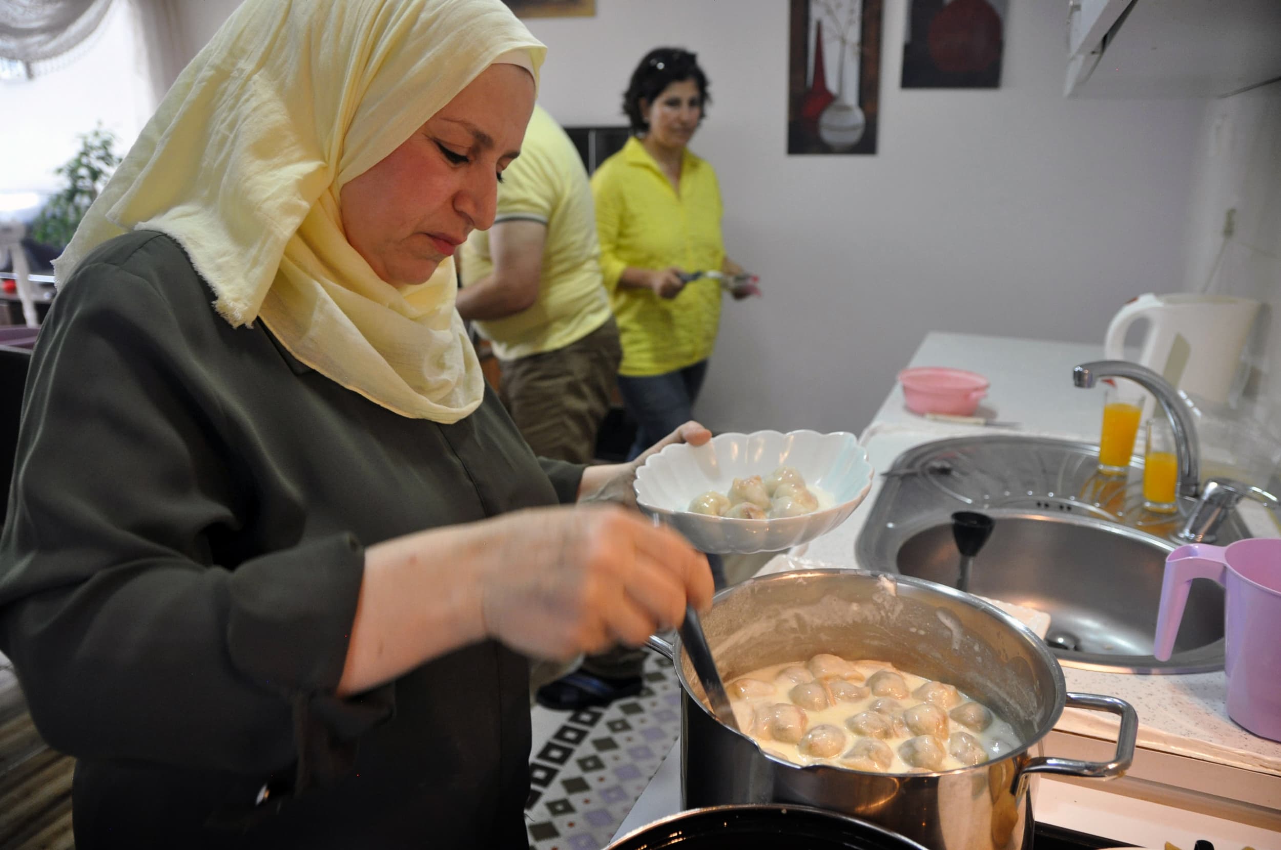 A woman stirs a steaming pot in a kitchen
