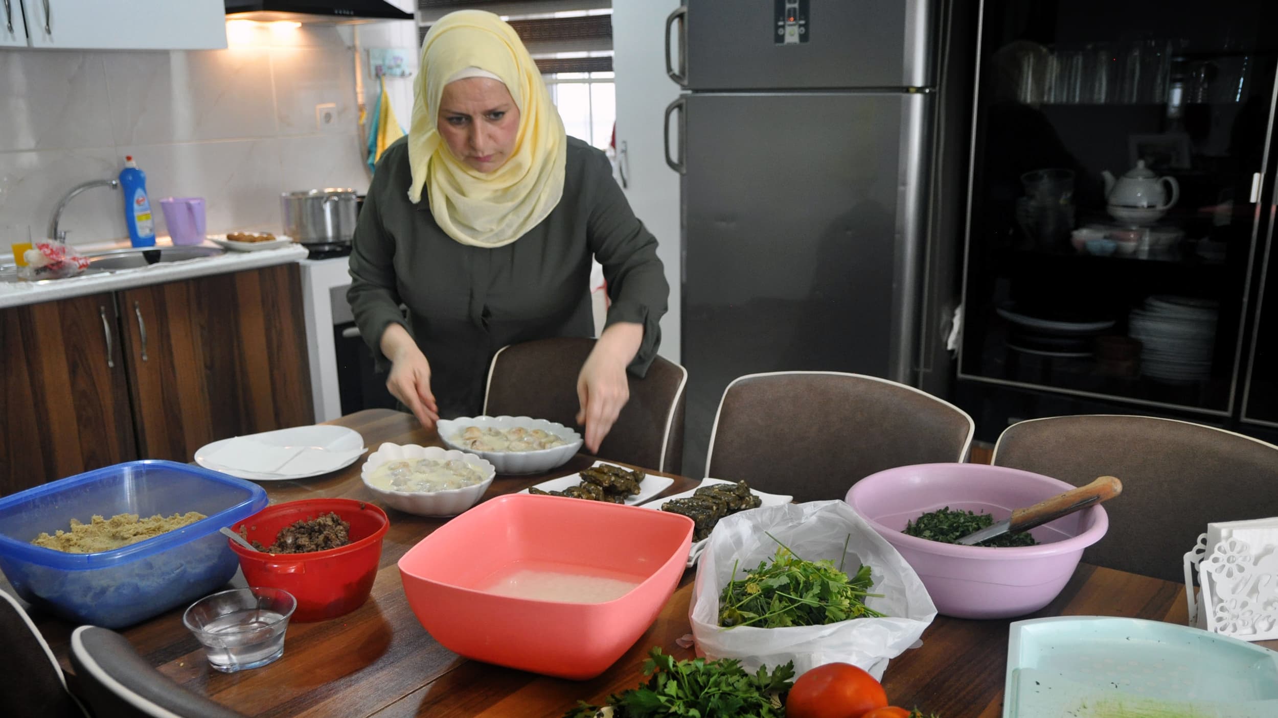 A woman stands over a spread of dishes in the kitchen