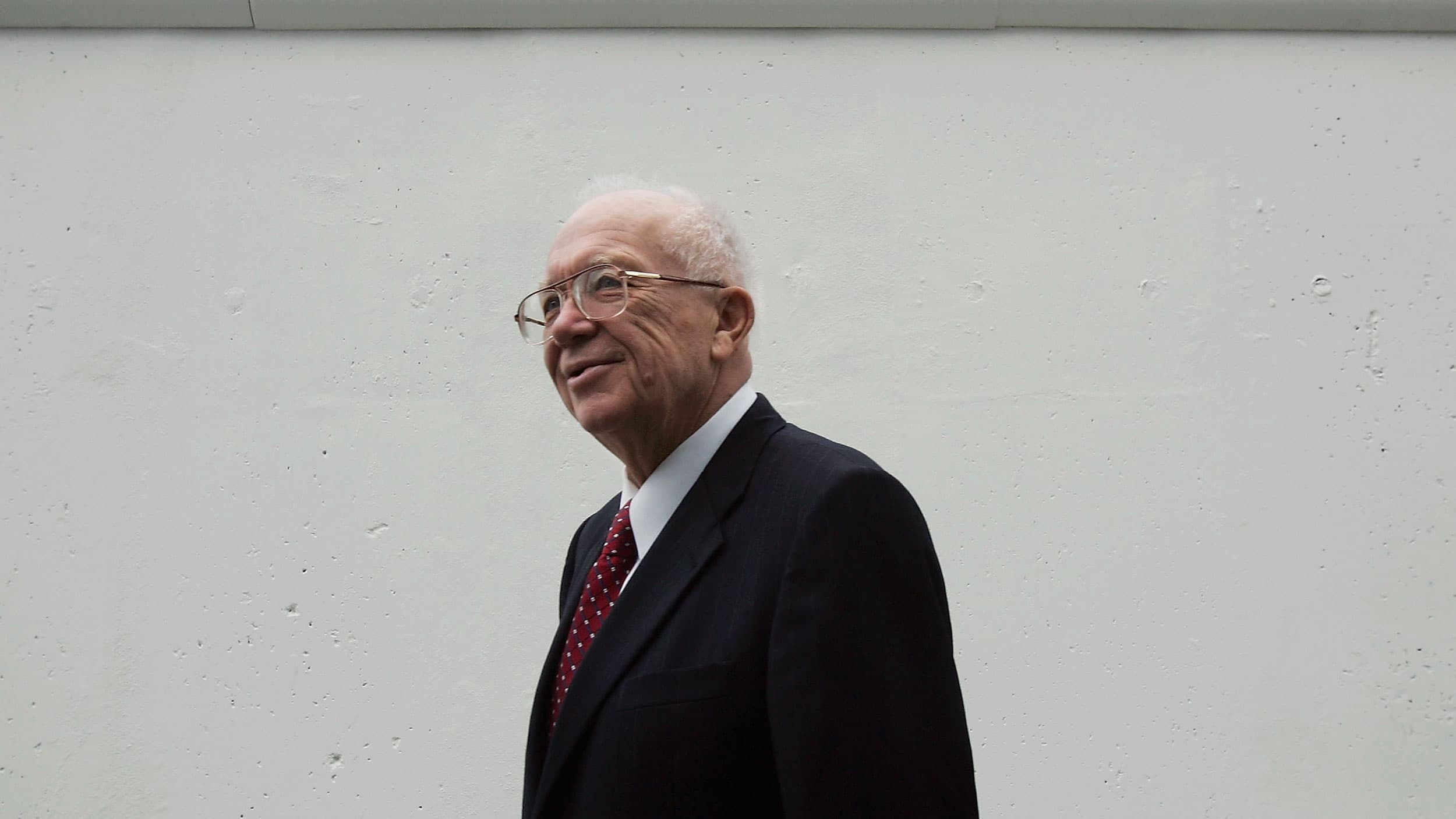 An elderly white man in front of a white background