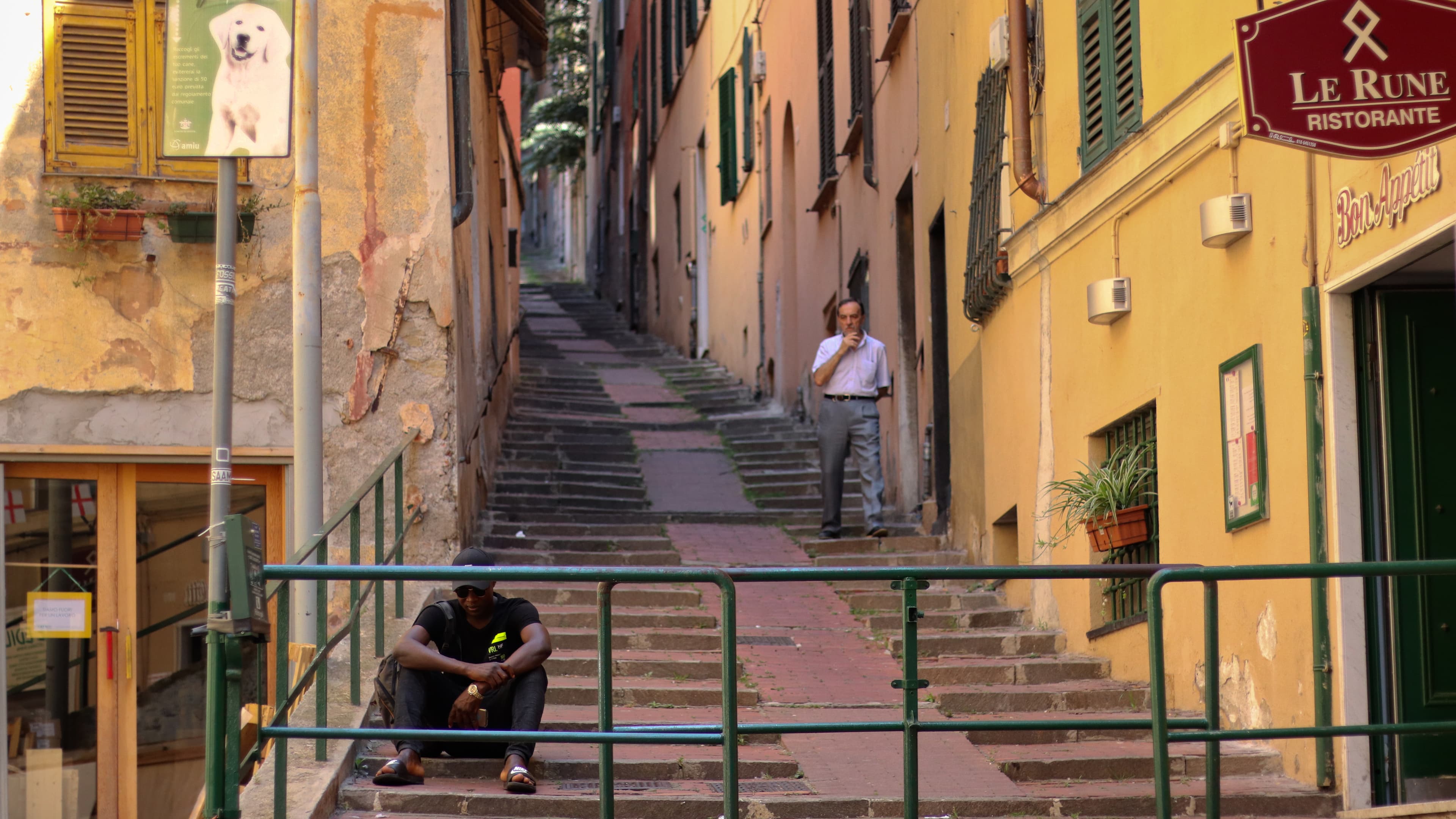 an asylum-seeker in Italy sits at the bottom of some stairs in Genoa