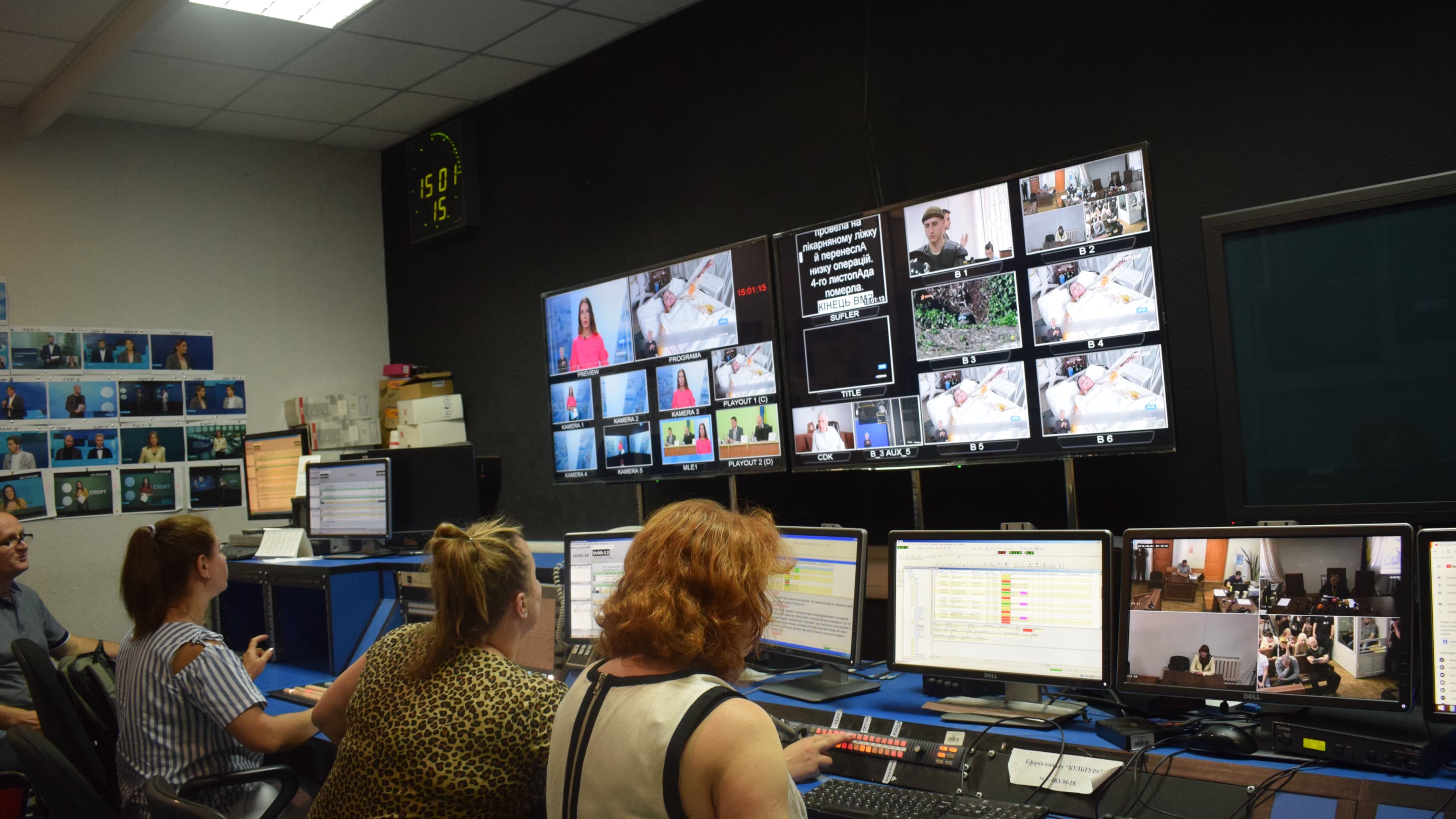 Media professionals sit in control room with brightly lit screens