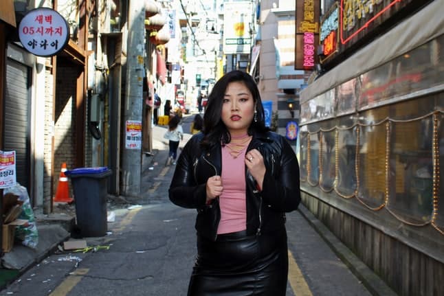 A woman poses on a busy urban street with lots of signage