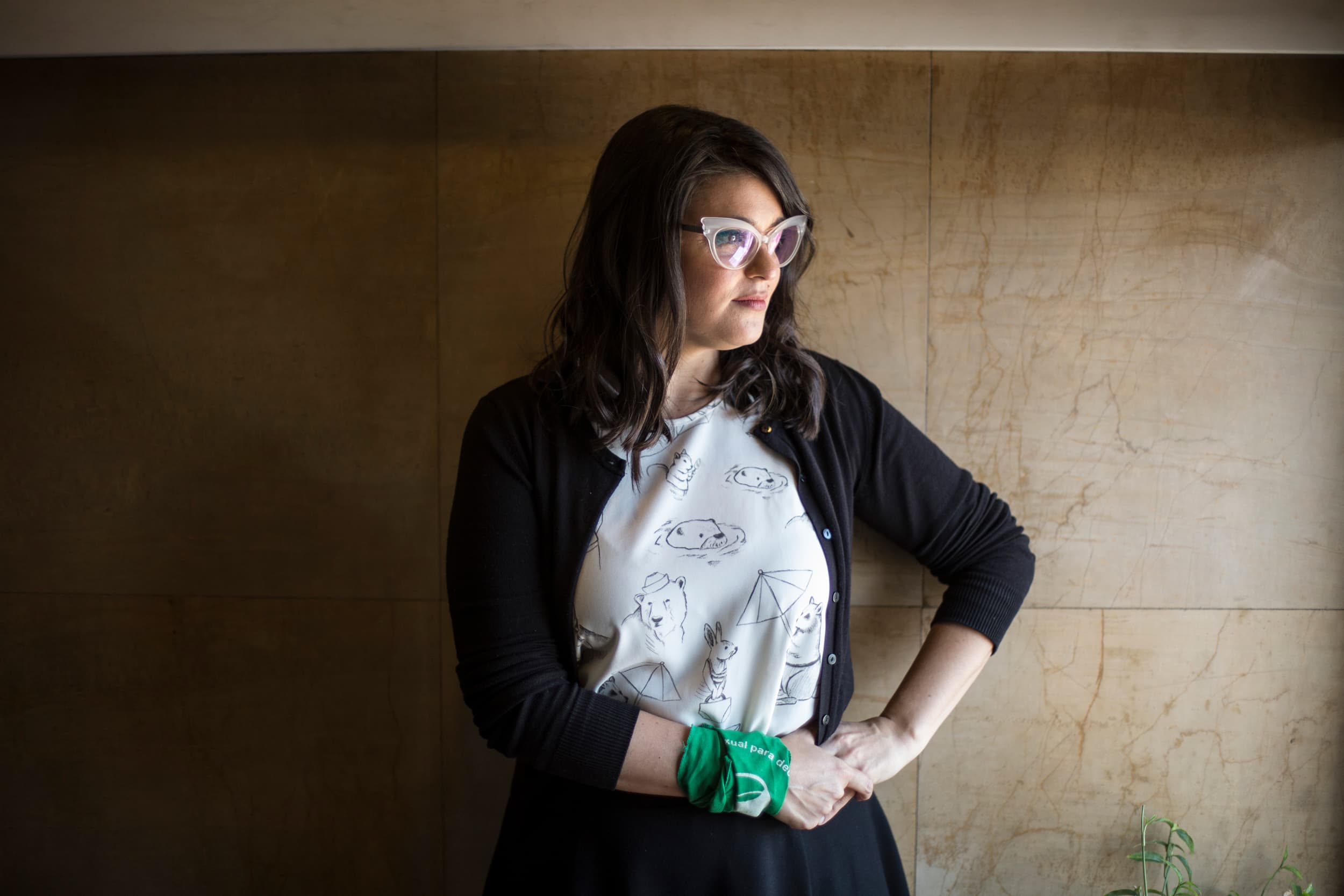 A woman posing against a wall.