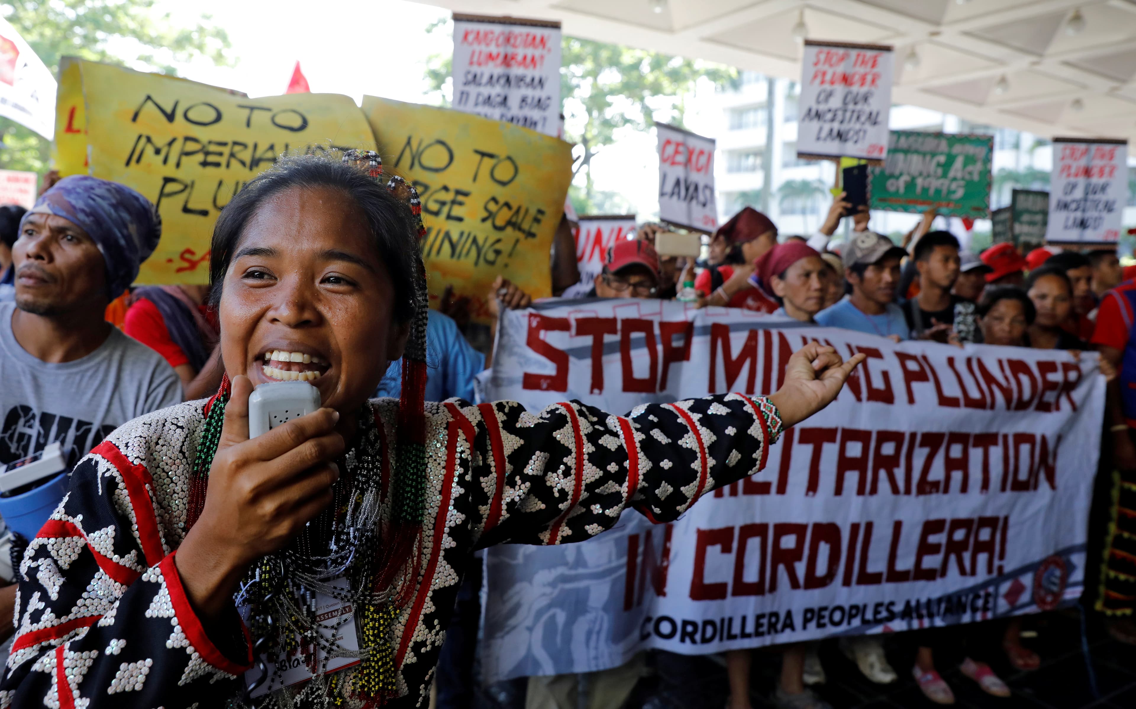 Protesters hold signs and yell during a protest.