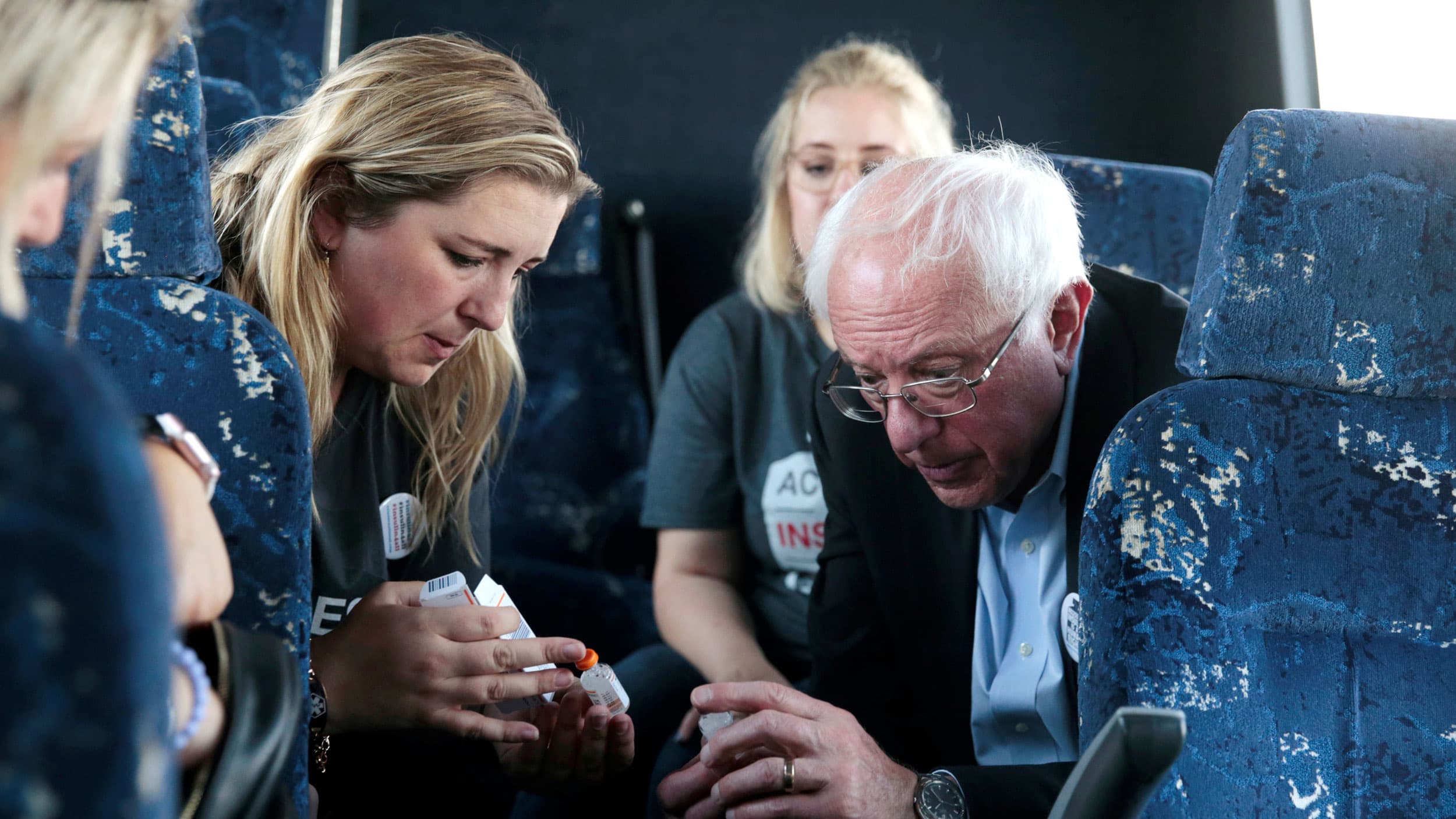 Bernie Sanders sits in a bus next to a woman, a diabetes patient