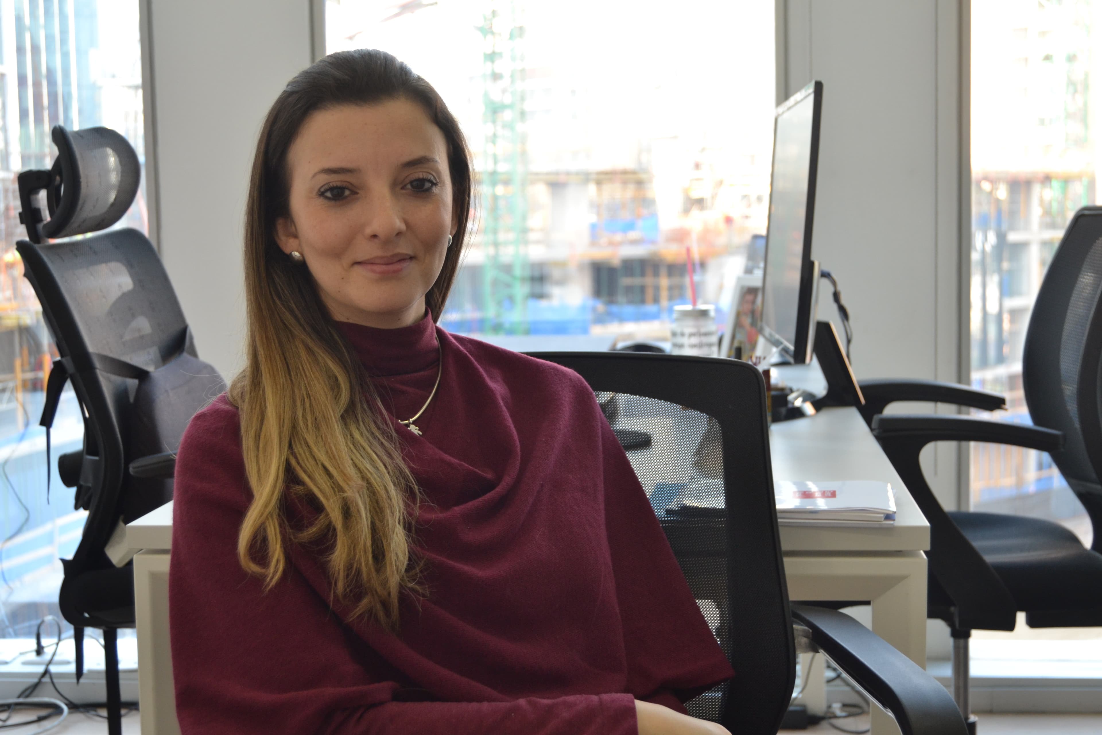 A woman poses for a photo at a desk.