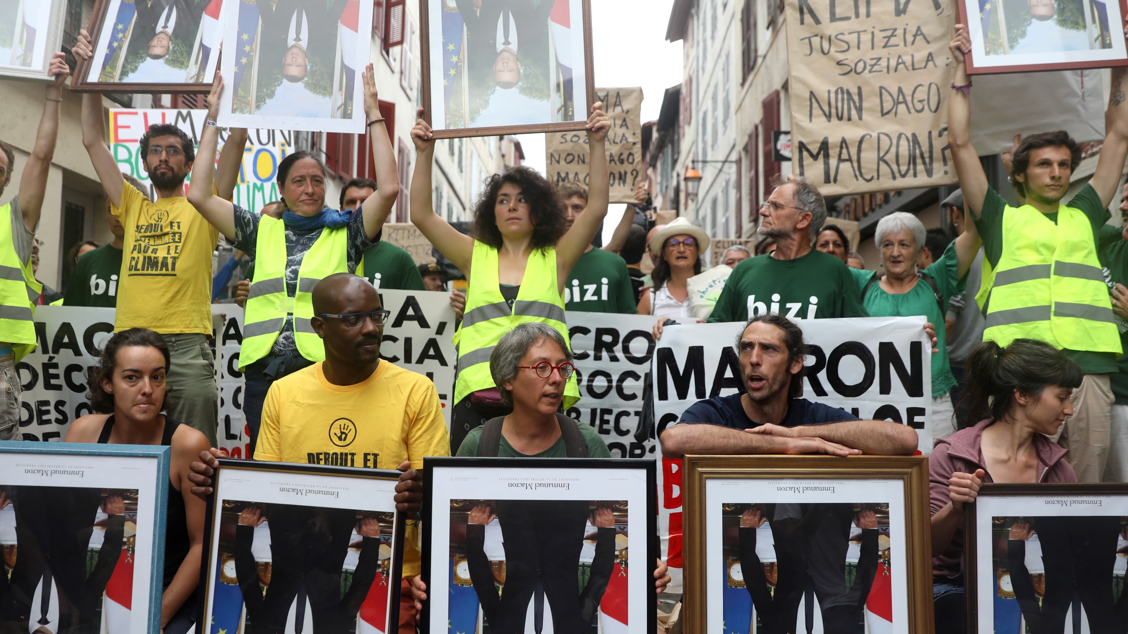 protesters hold signs of macron upside down