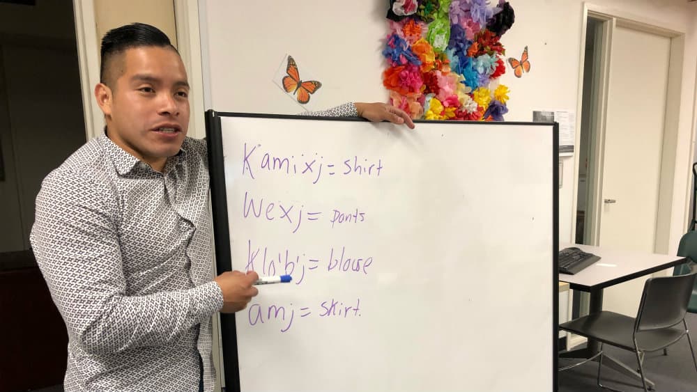 A man stands next to a white board.
