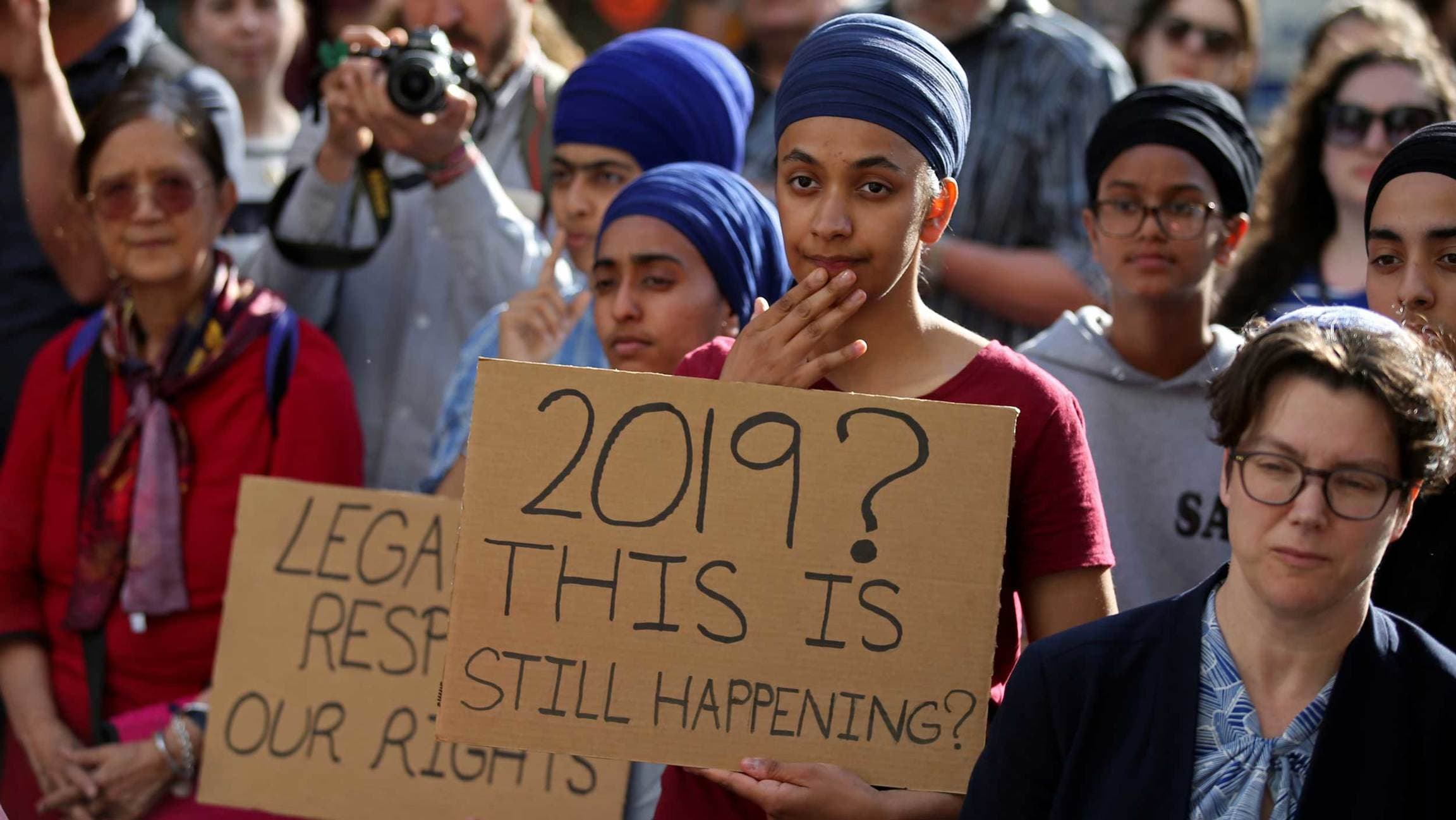 Protesters hold signs that 2019? This is still happening?
