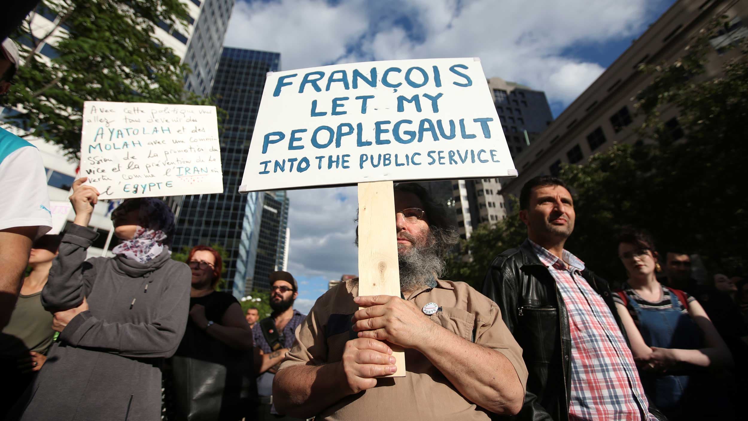 A man holds a sign that says "Let my peoplegault into the public service"