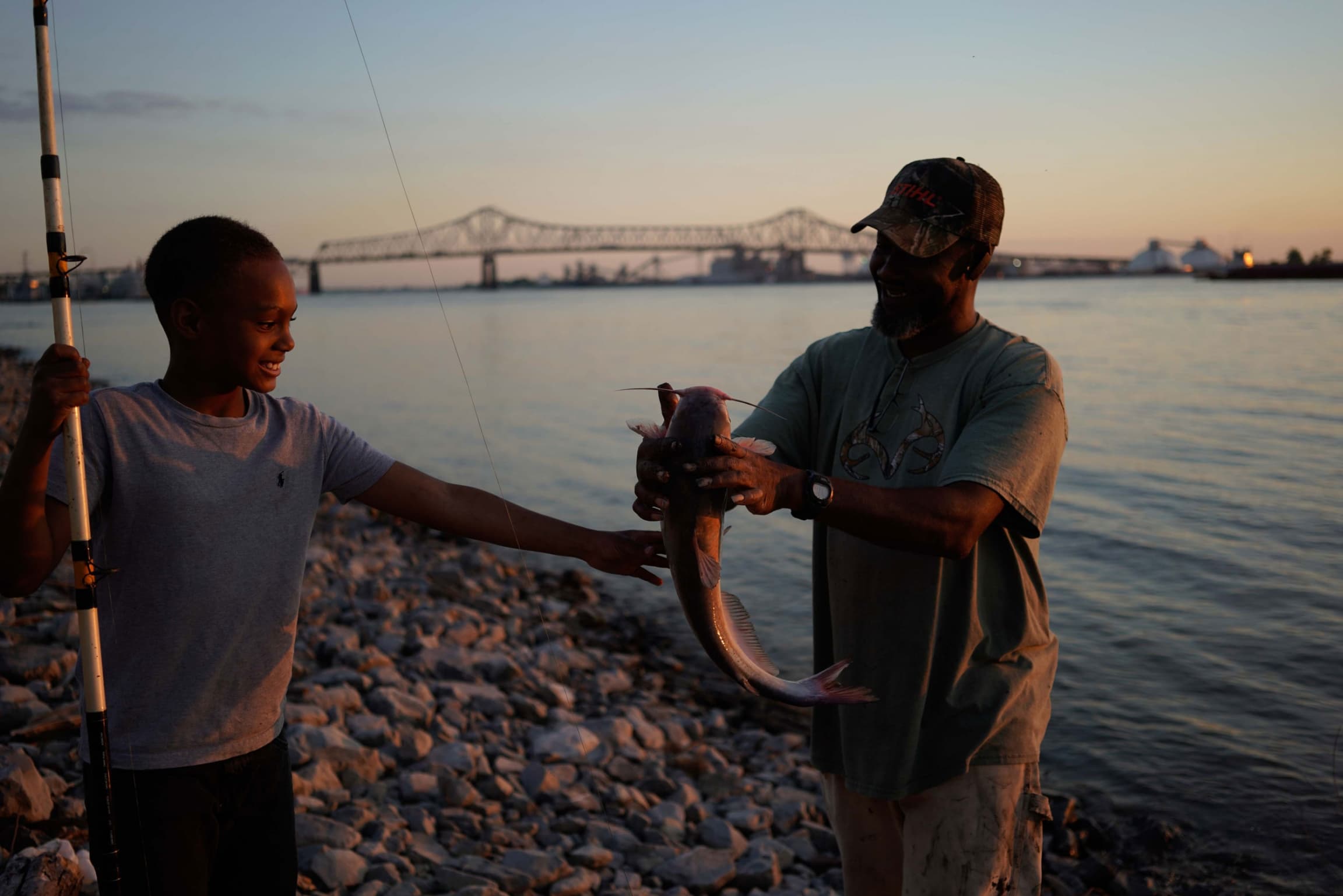A man is shown with a large fish next to a younger boy.