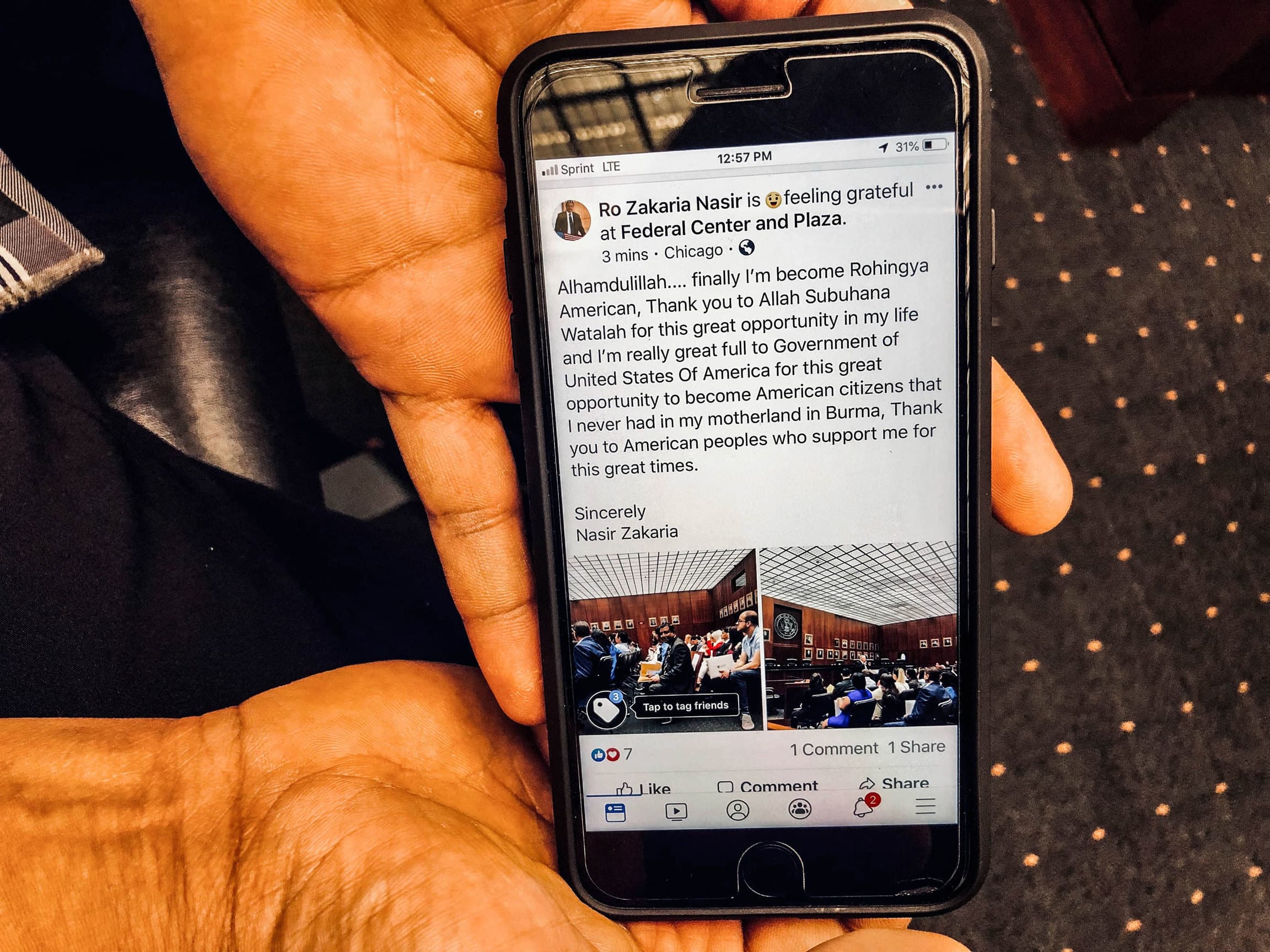 A close-up photo of a cellphone showing a Facebook status.