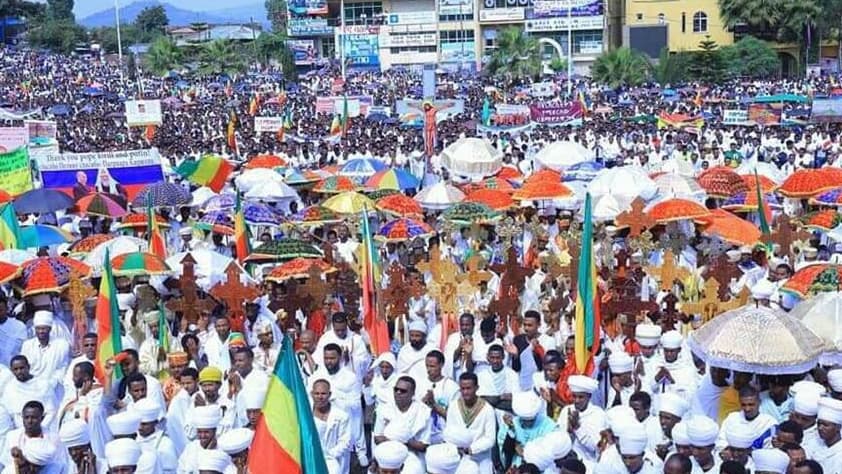 A mass of protesters wearing white and carrying Ethiopian flags gather in the street