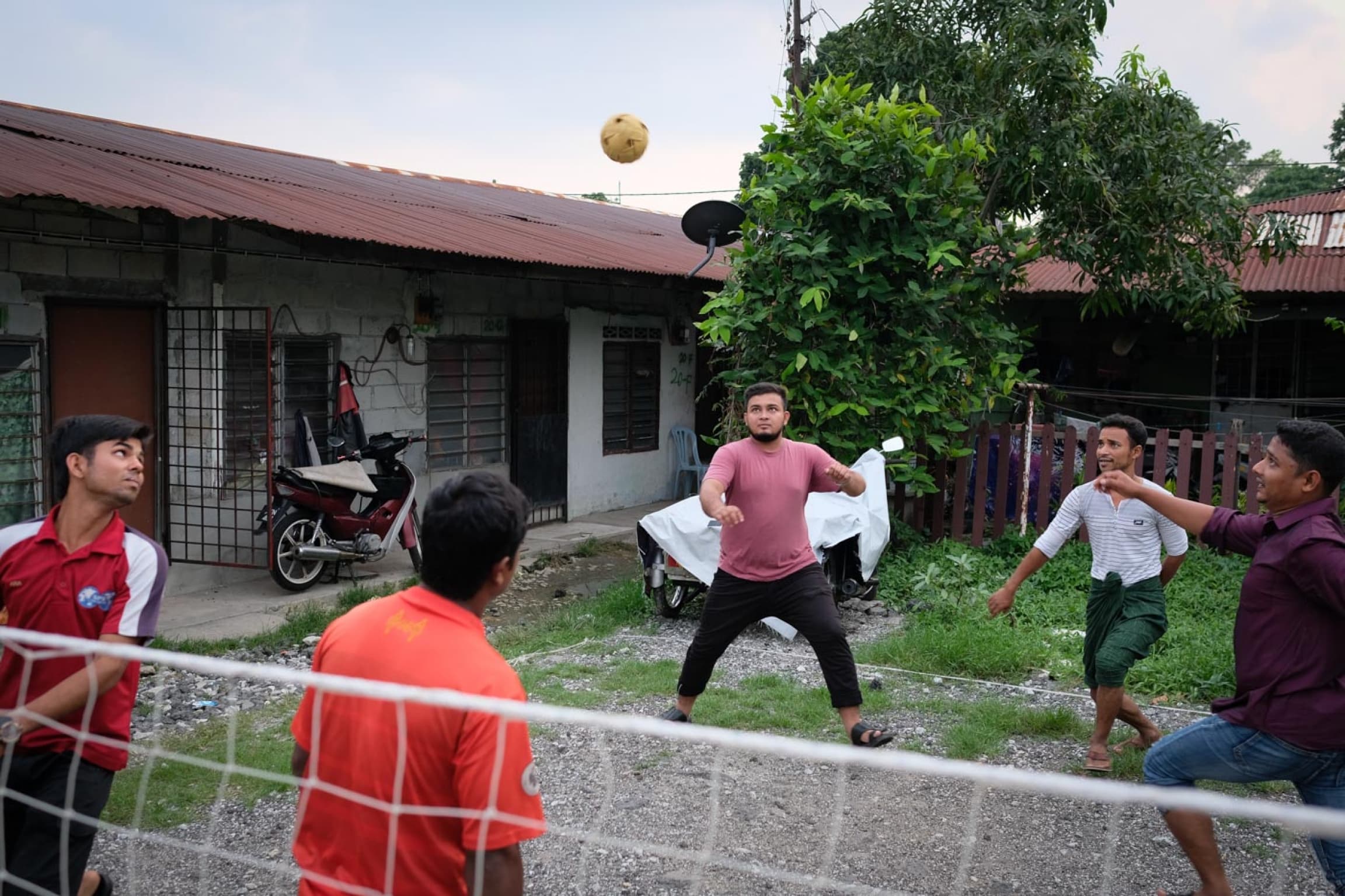 A group of young men play kick volleyball with a net
