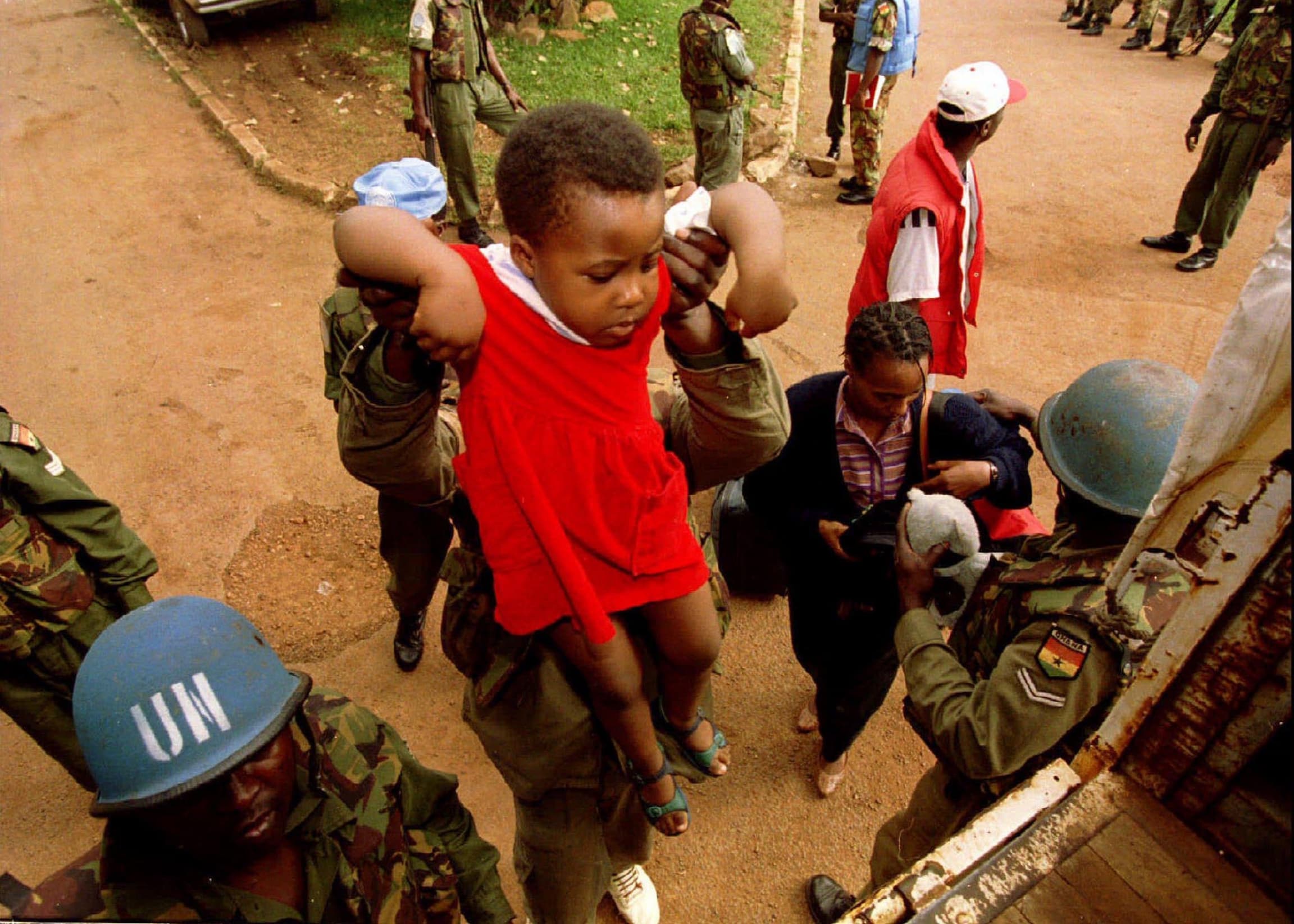 UN peacekeepers hold up a child.