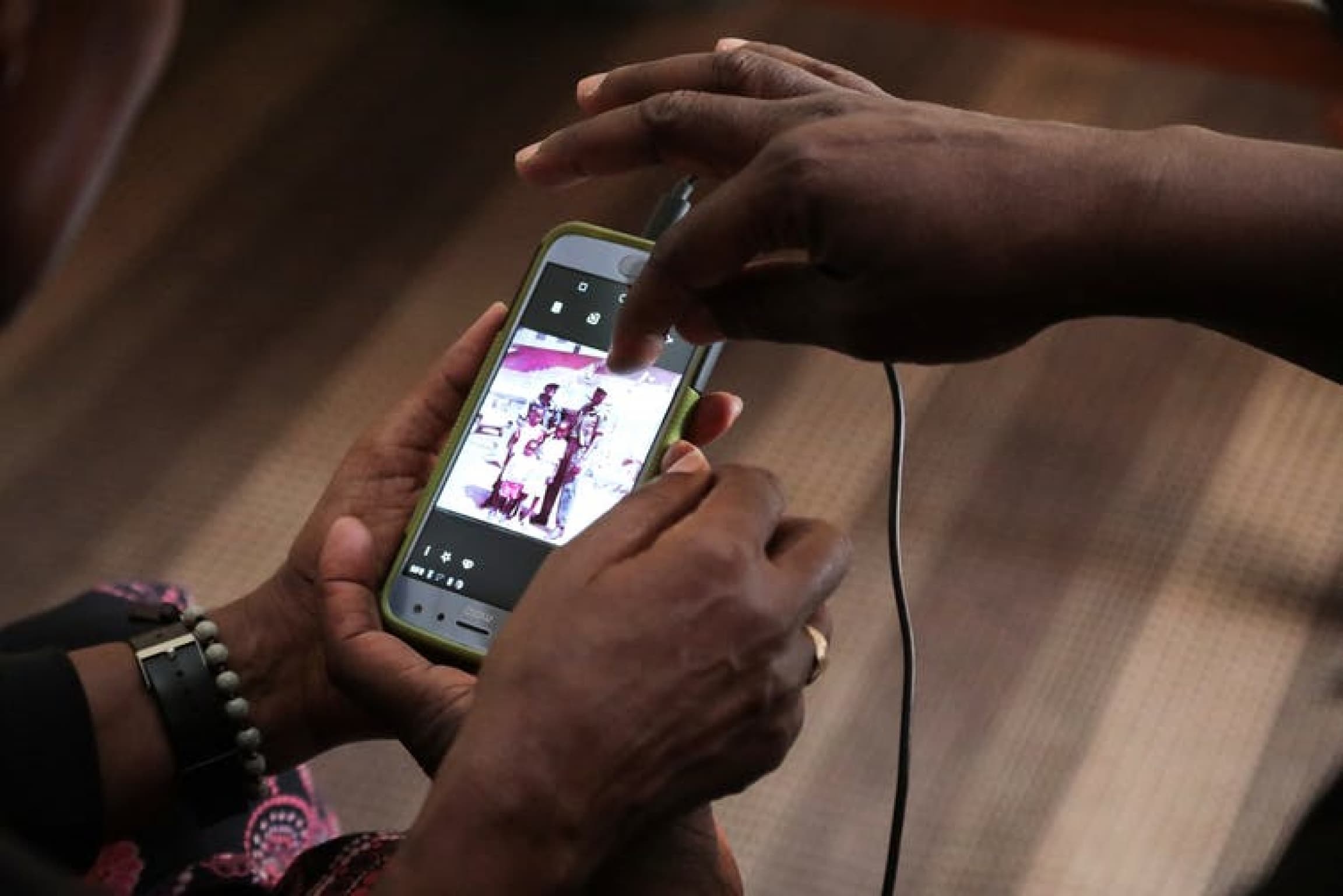 A man holds a phone with a picture of himself.