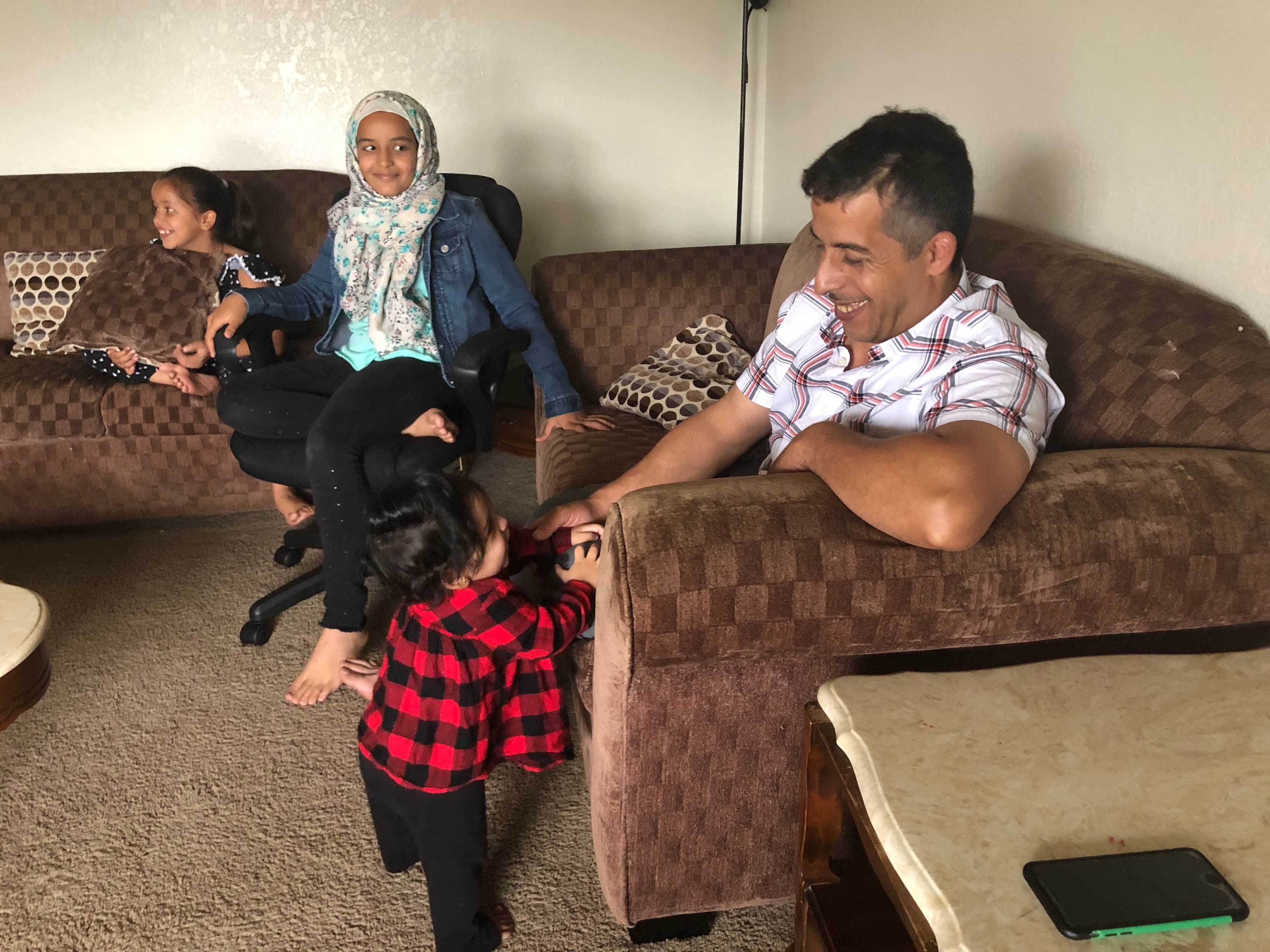 A man plays with his daughters in their living room.