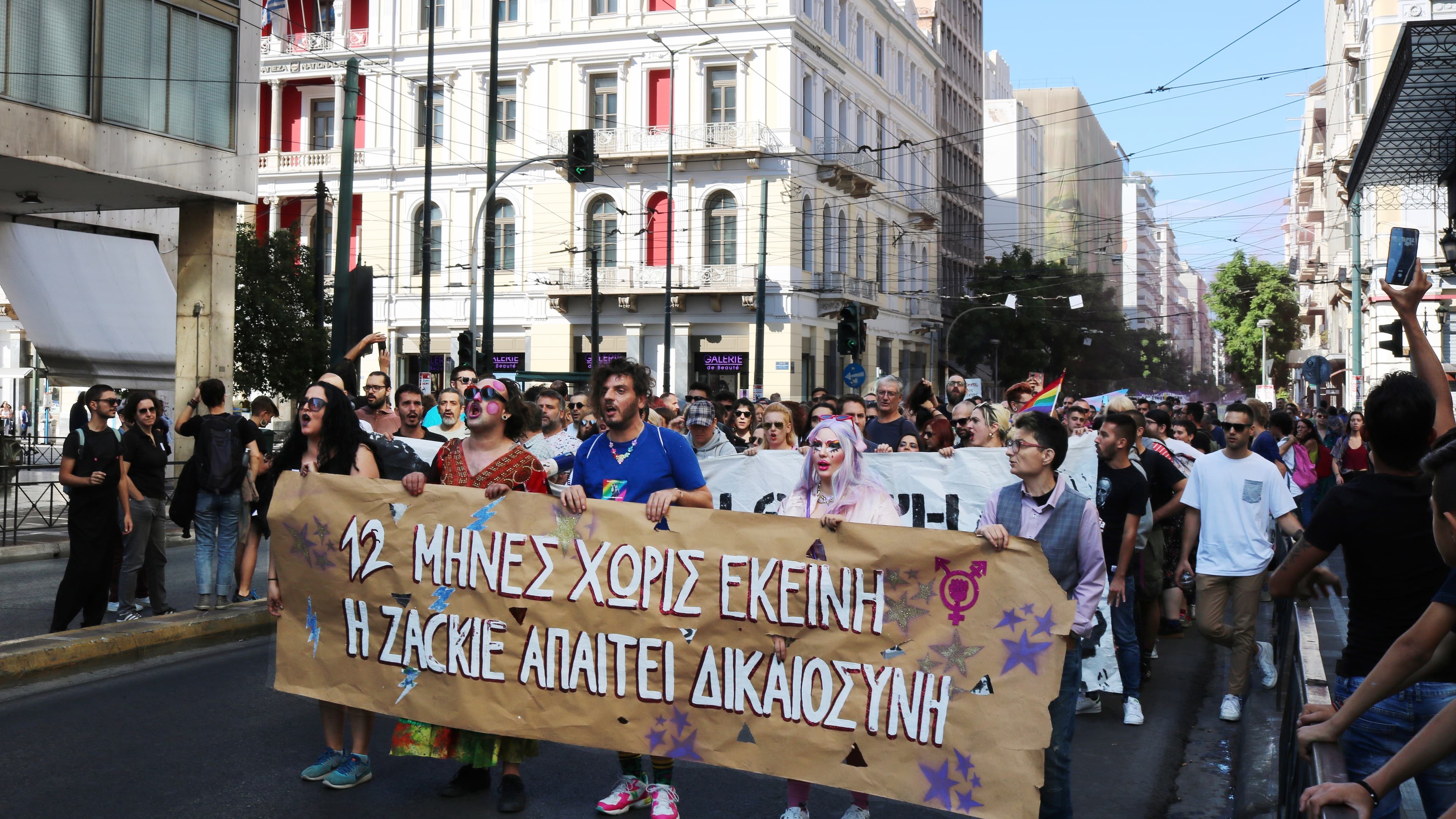 Marchers stand behind a large white banner as they move through a street