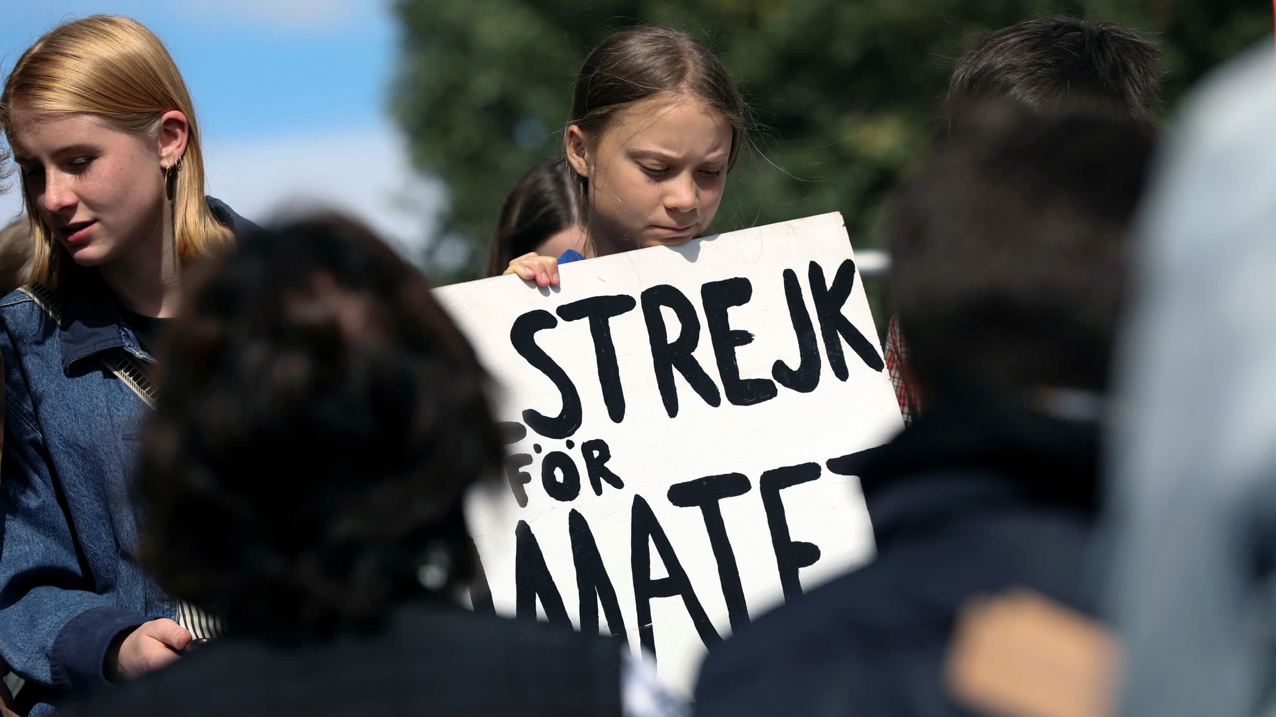 Climate change environmental teen activist Greta Thunberg participates in a climate strike rally and looks down at a placard
