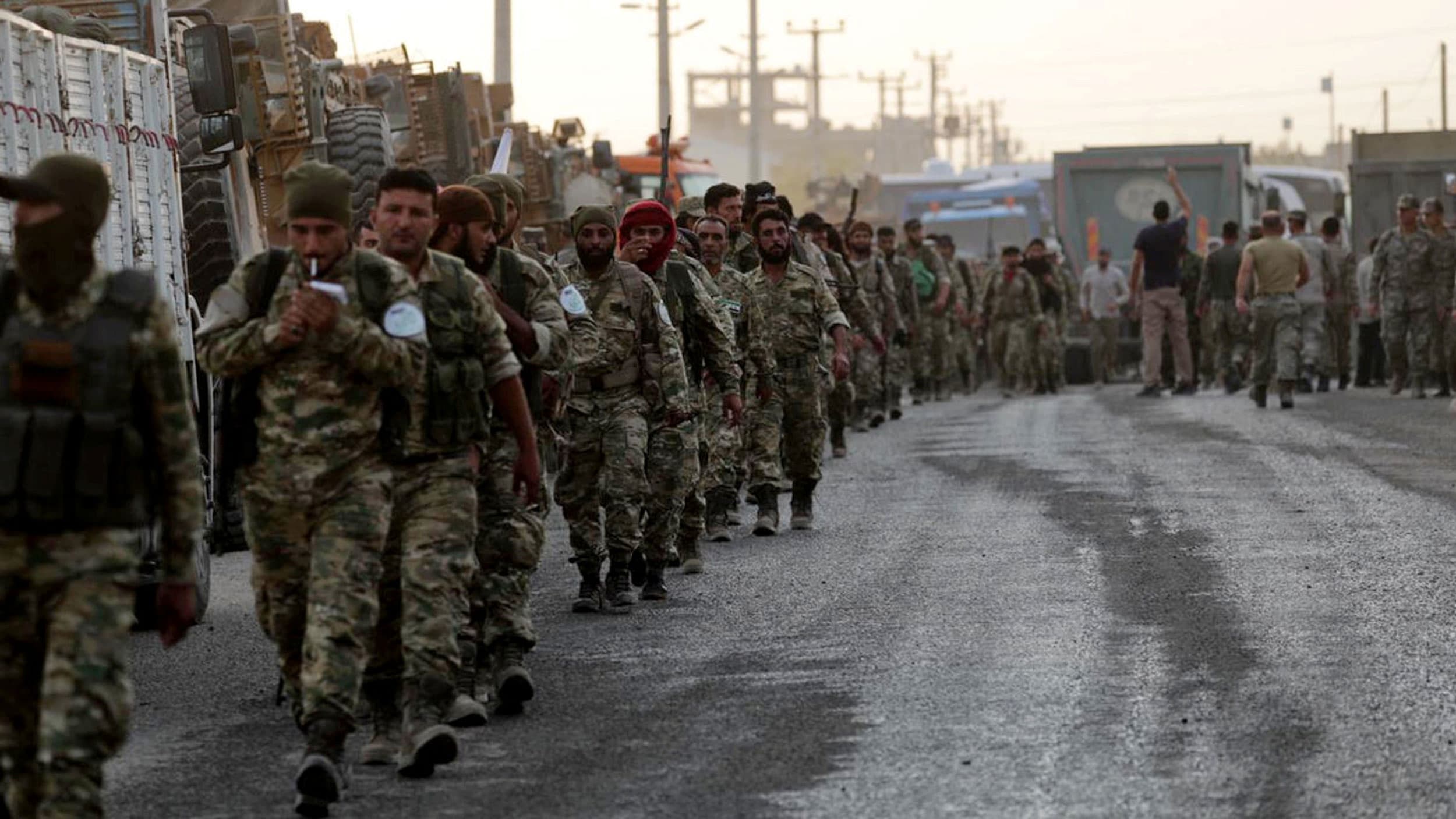 Turkey-backed Syrian rebel fighters walk together in the border town of Akcakale in Sanliurfa province, Turkey, on Oct. 11, 2019.