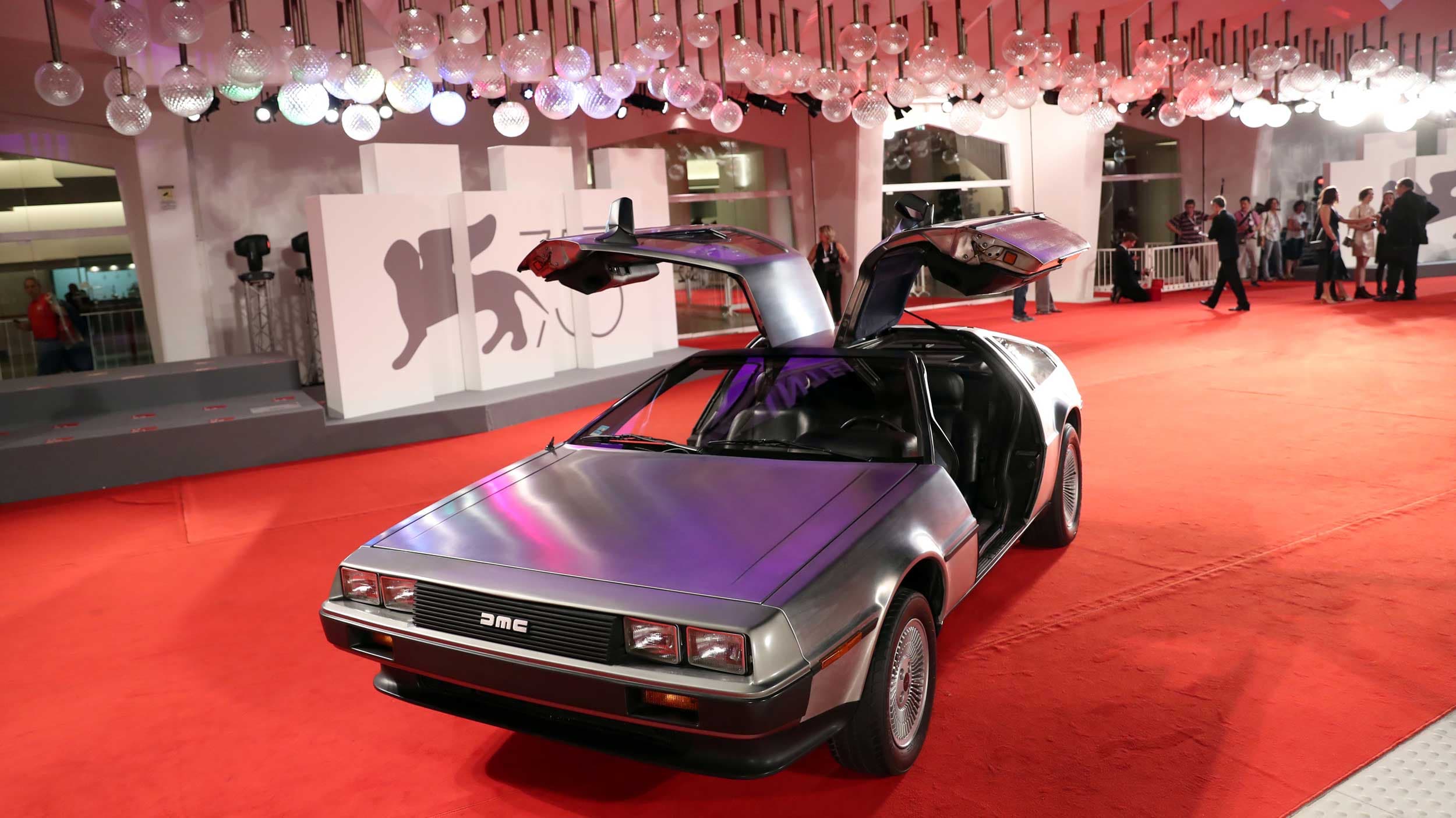 A Delorean car sits with it's iconic doors open on a red carpet
