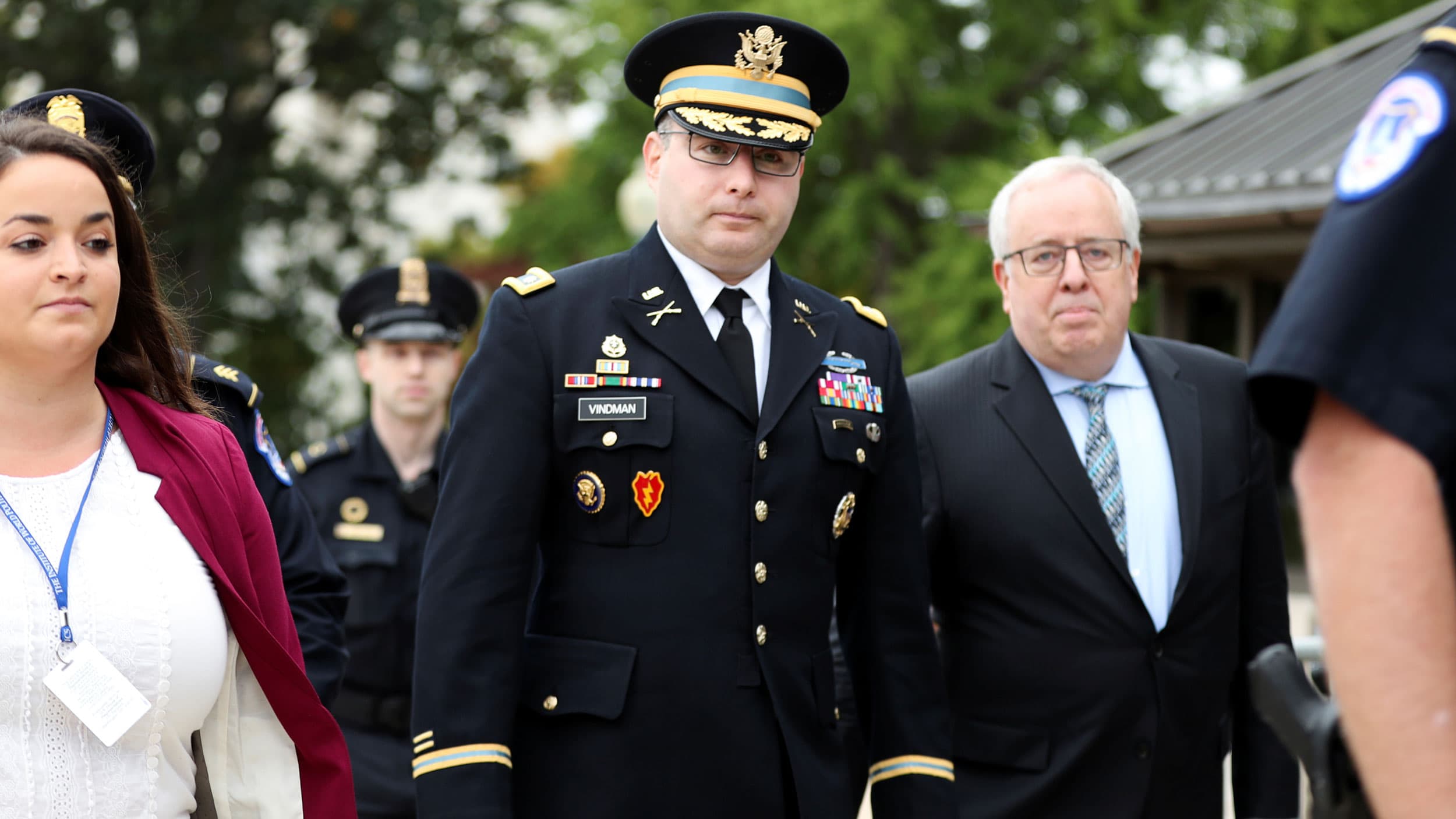 A man in a military uniform is walking with other people around him
