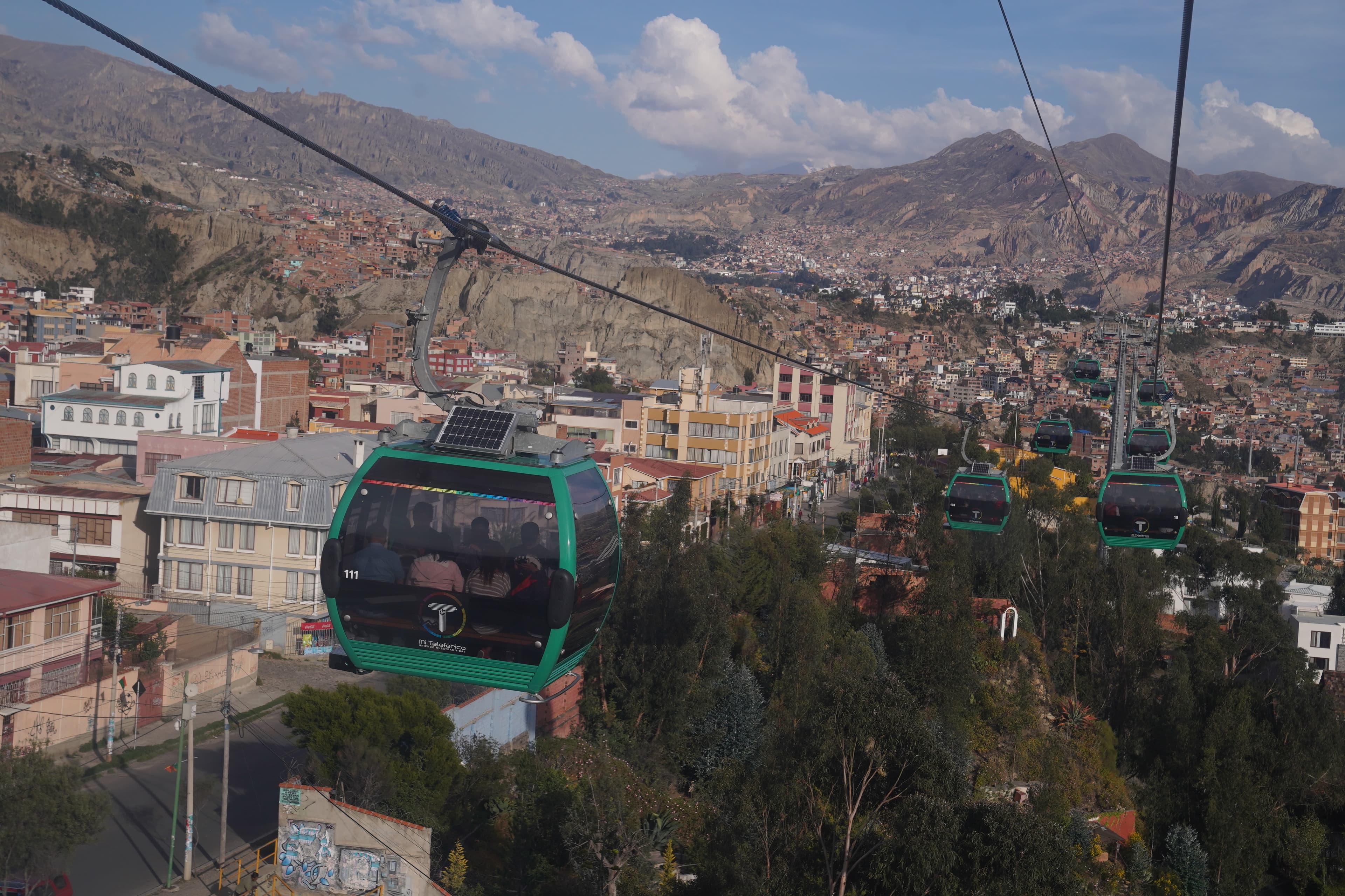 A cityscape with cable car system with views of the mountains in the background