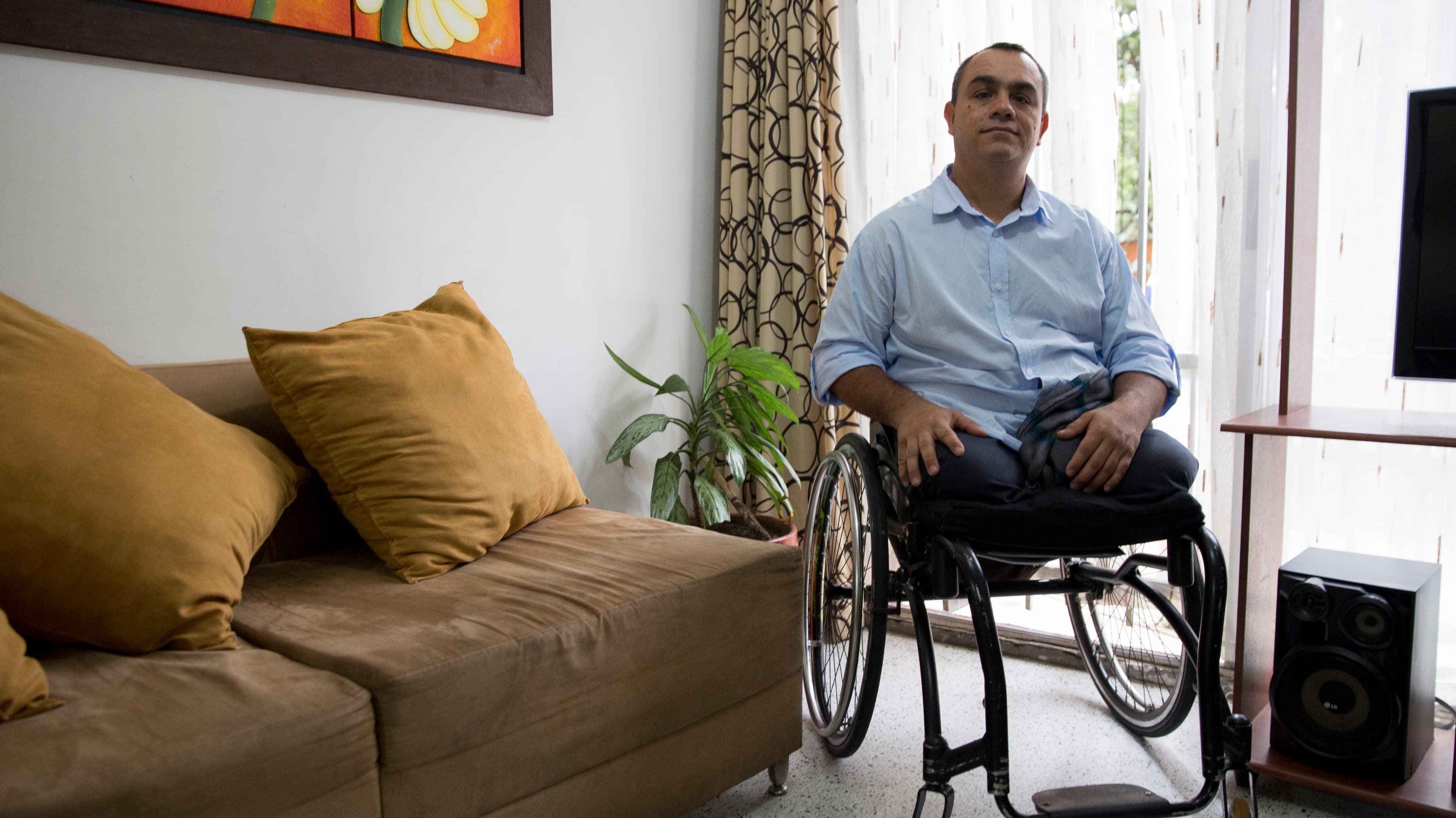 A man with no legs sits in a wheelchair in his living room