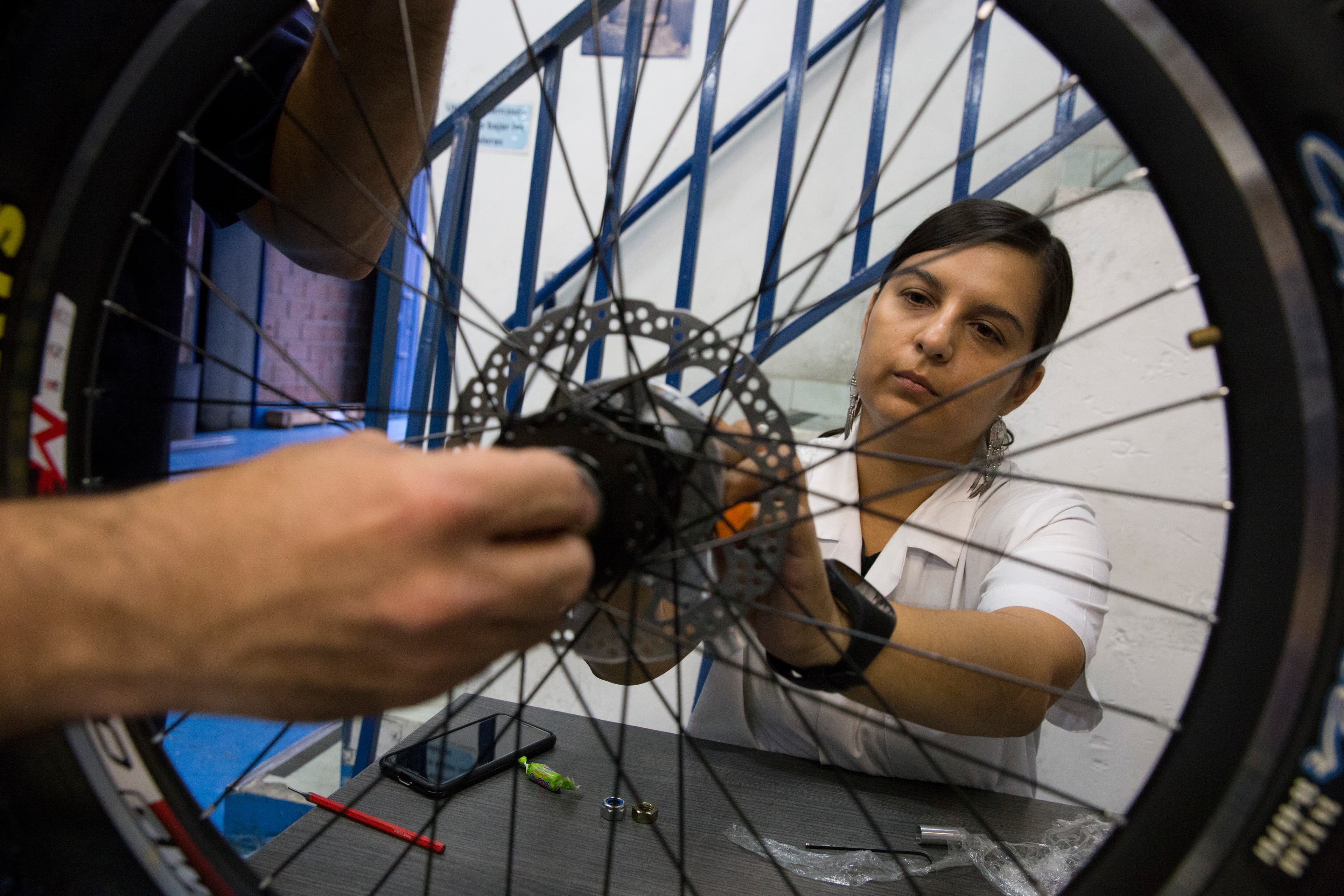 A woman looks at the spoke of a wheel
