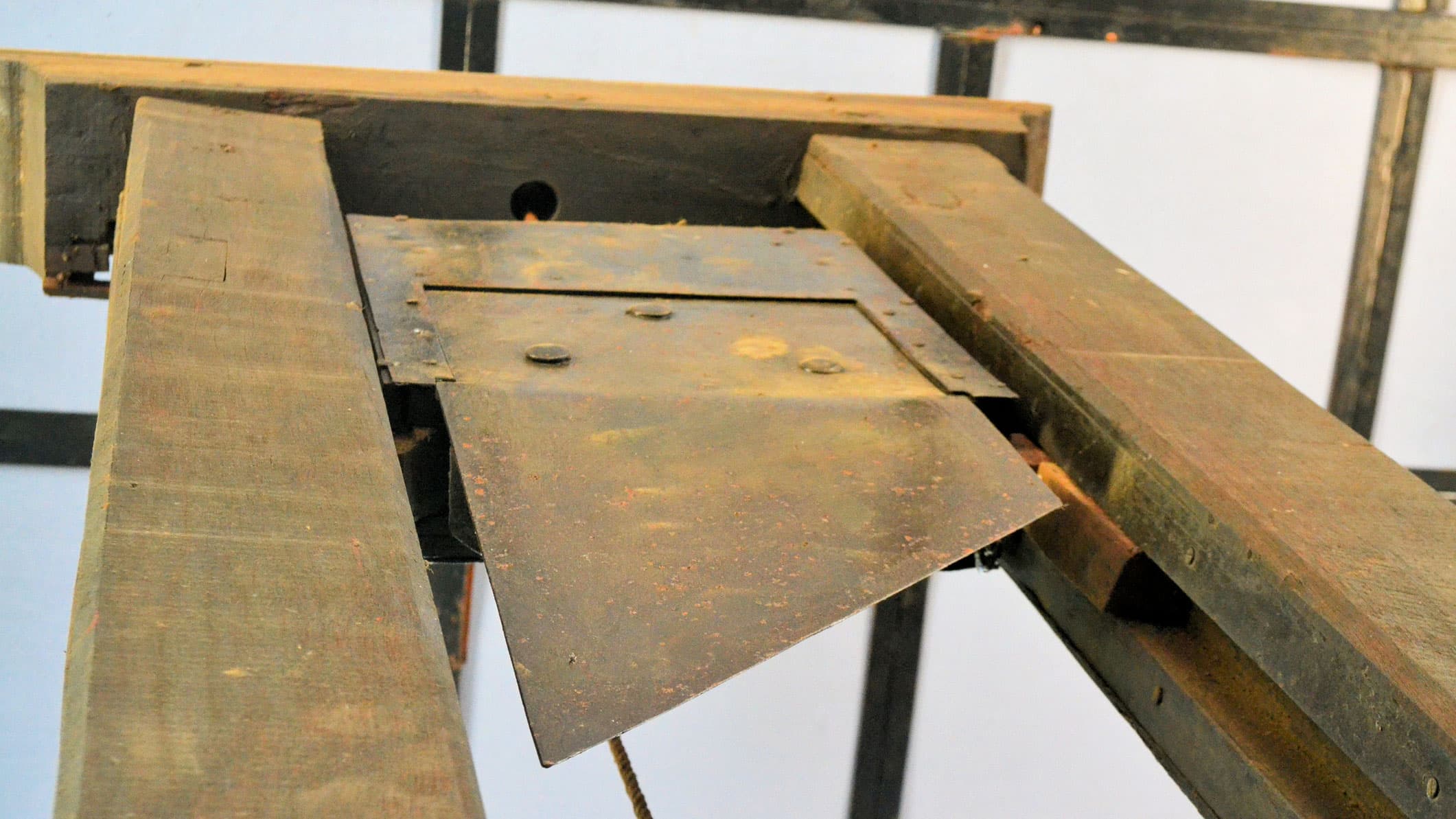An old, wooden guillotine shows sharp blade.