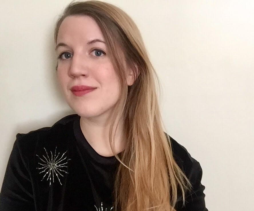 a woman in a black sweater posses for a  photo.