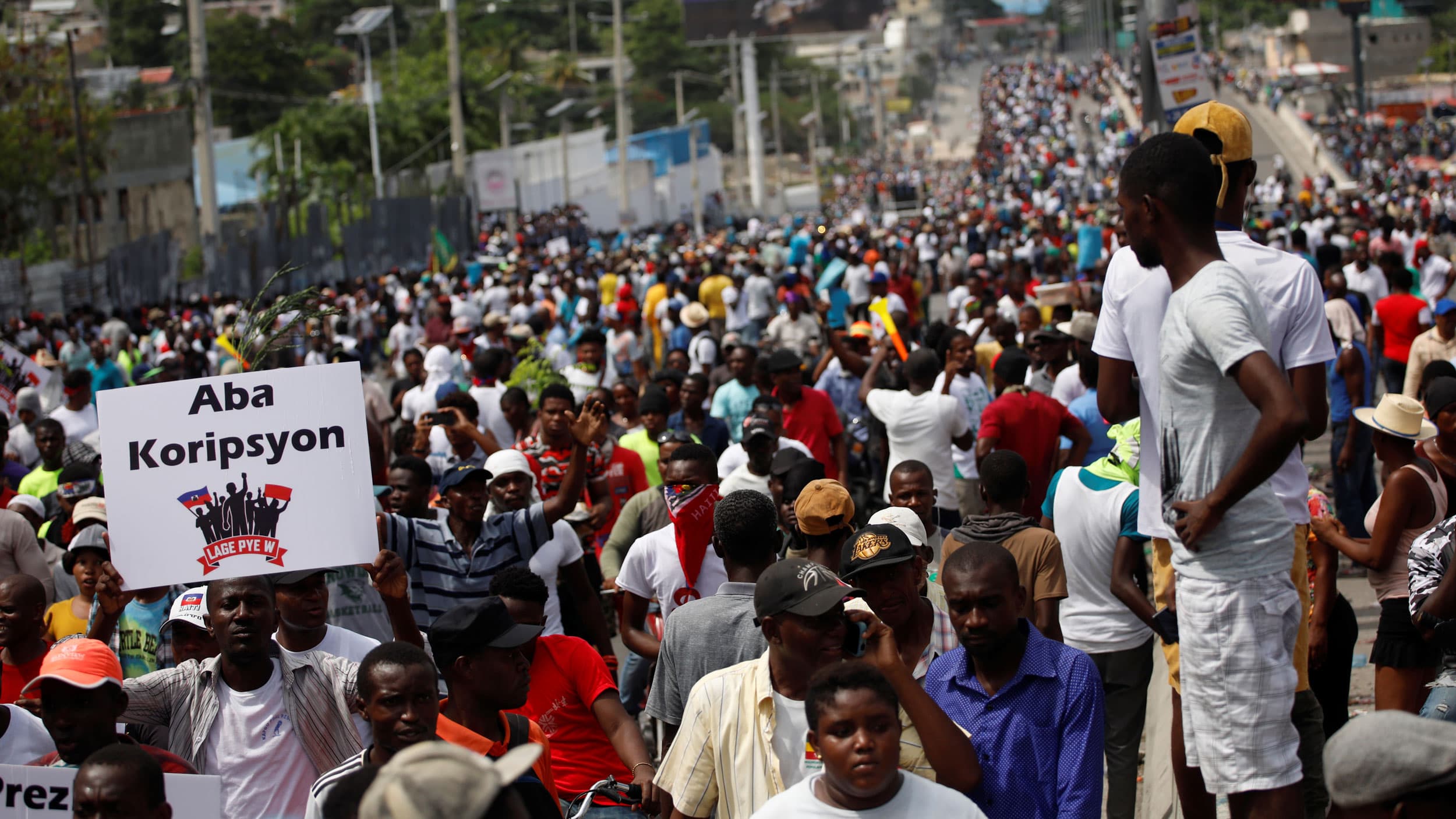 A crowd of marchers fills a street. Some hold signs.