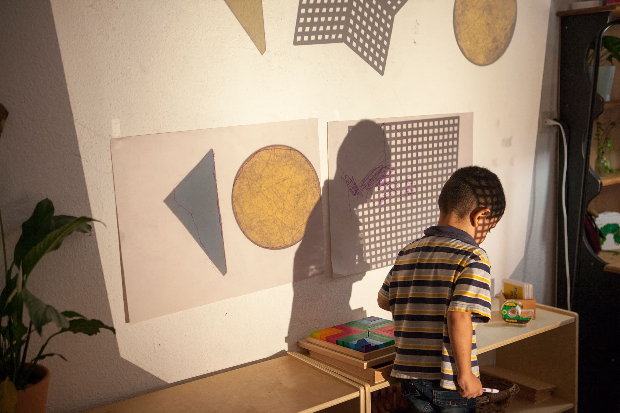 A child is shown walking past a table with wooden toys.