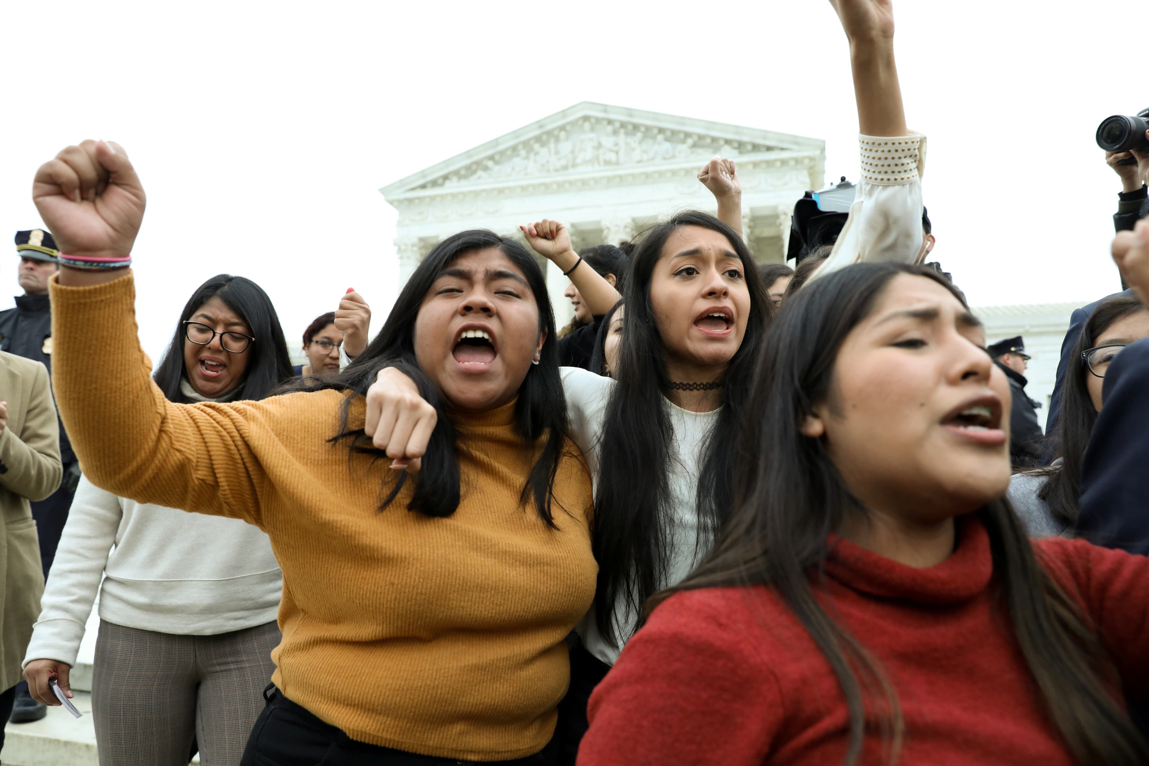 DACA plaintiffs walk arm-in-arm down from the US Supreme Court.